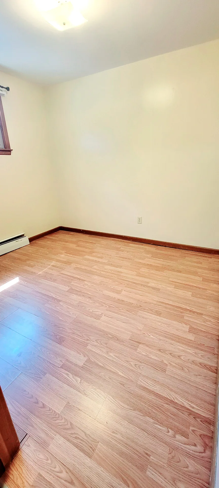 2040 Iuka Ave. 3A bright bedroom with laminate floors, window light, and baseboard heat