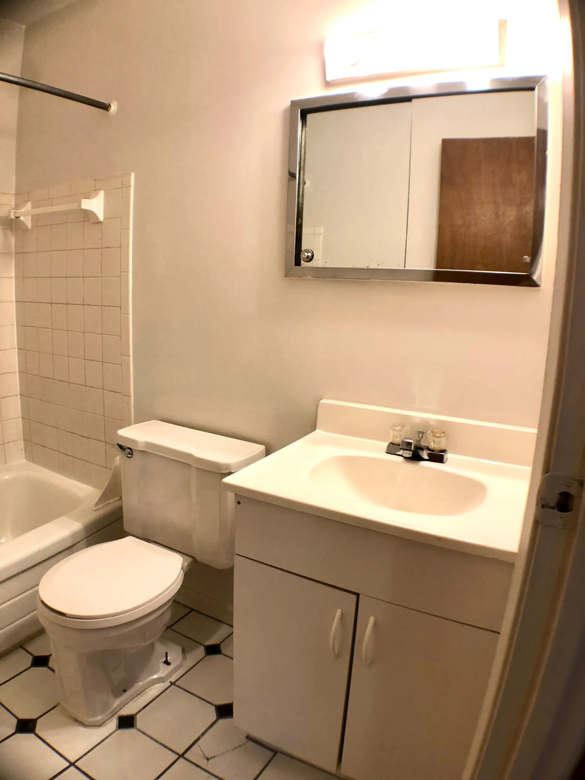 1827 N 4th St. Unit 4 bathroom with white vanity, tiled tub surround, and checkered tile floor