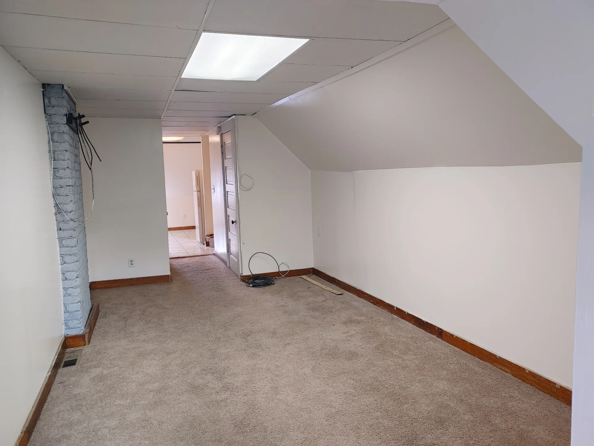 89 E Woodruff Ave. Unit C bedroom with sloped ceilings, painted brick chimney, and carpet