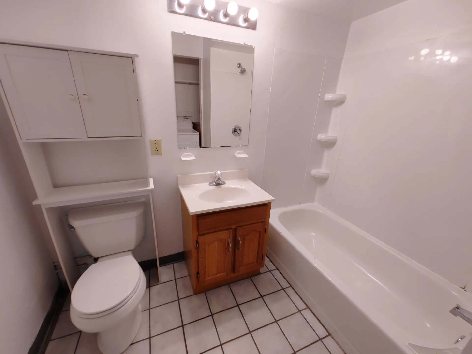 Rear unit bathroom with tub/shower surround, wood vanity and upper storage