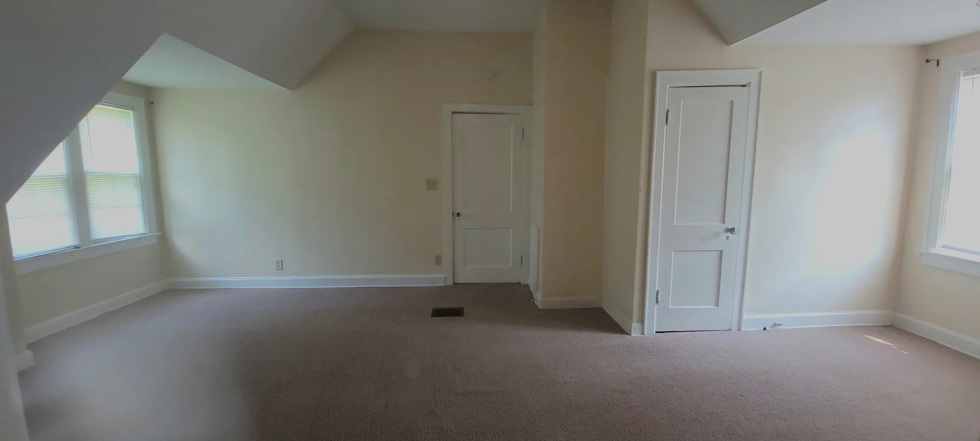 2054 Iuka Ave. C large carpeted bedroom with sloped ceilings, double windows, and extra storage doors