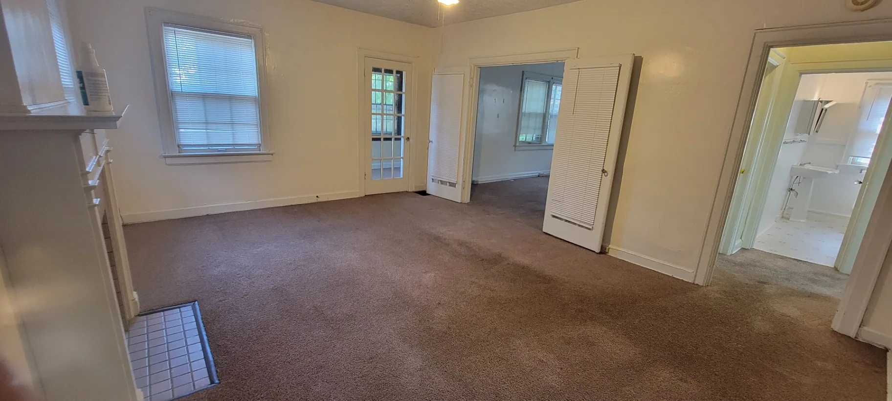 2044 Iuka Ave. D living room with fireplace mantle, French door to sunroom, and bathroom entry