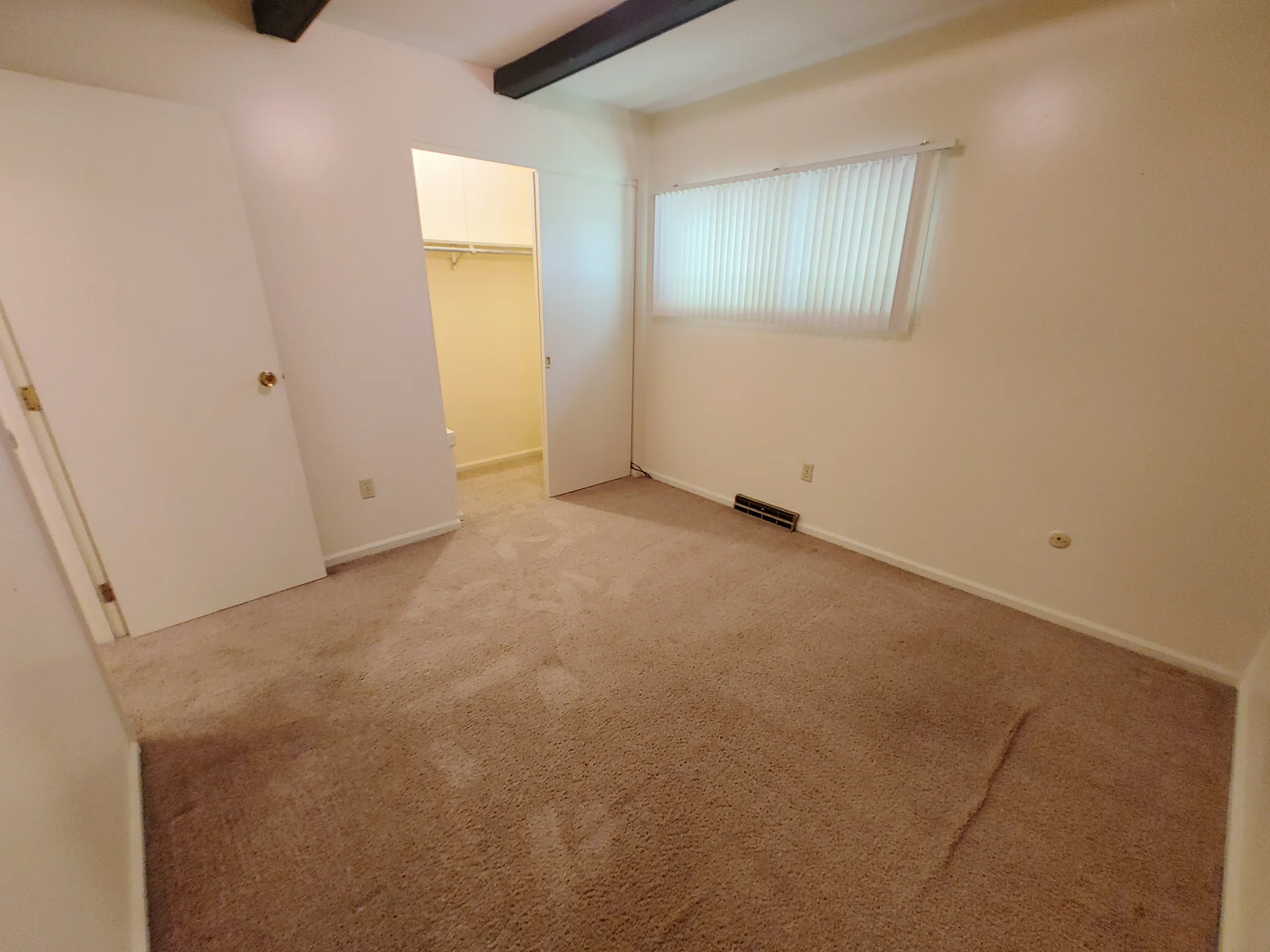 2020 Iuka Ave. bedroom with large window, vertical blinds, and entry to walk-in closet