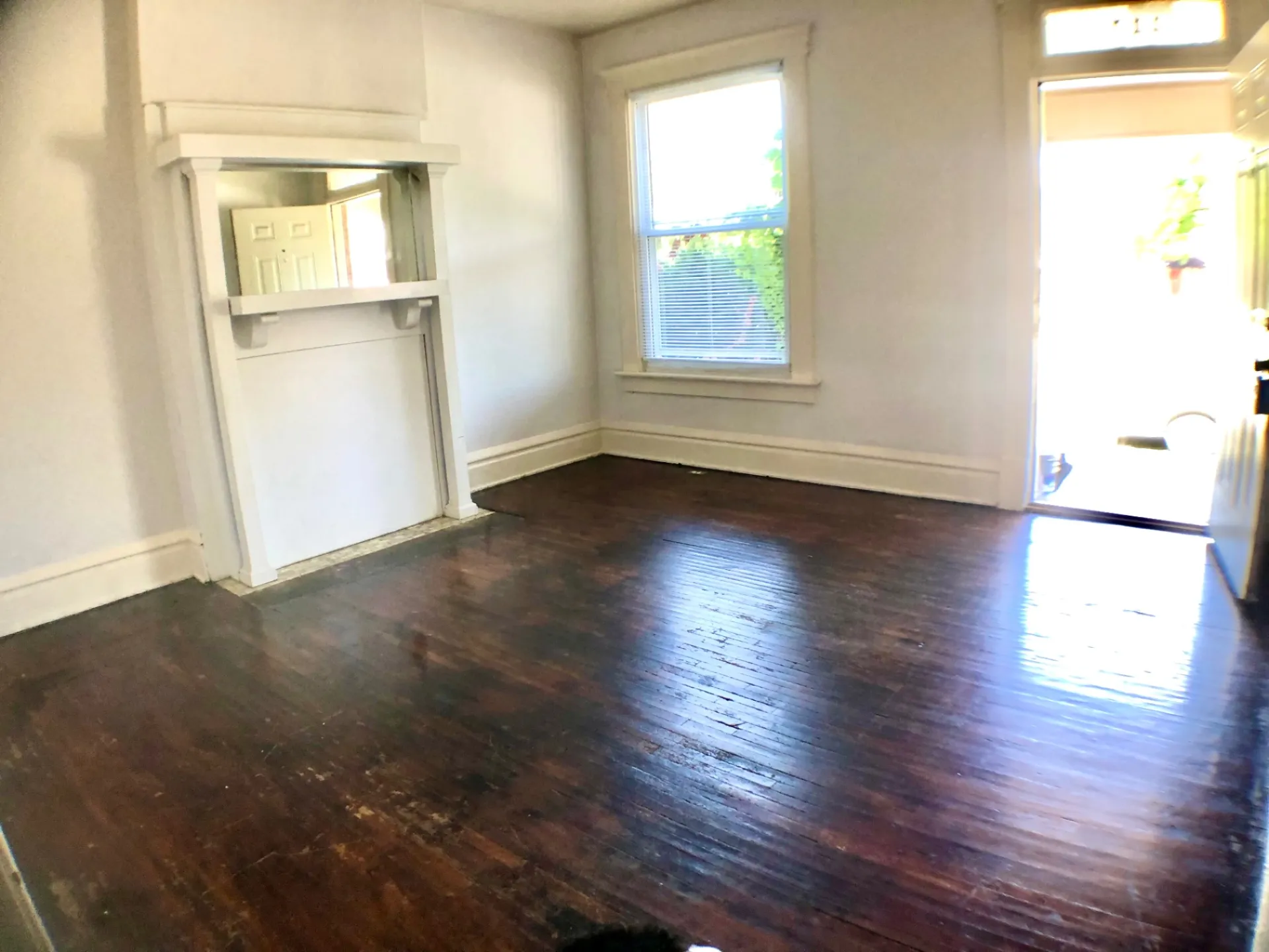 117 W 9th empty living room with refinished hardwood floors and mantel