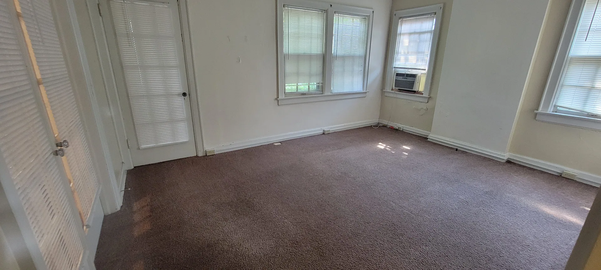 2044 Iuka Ave. D enclosed sunroom with wraparound windows, window AC, and neutral carpet
