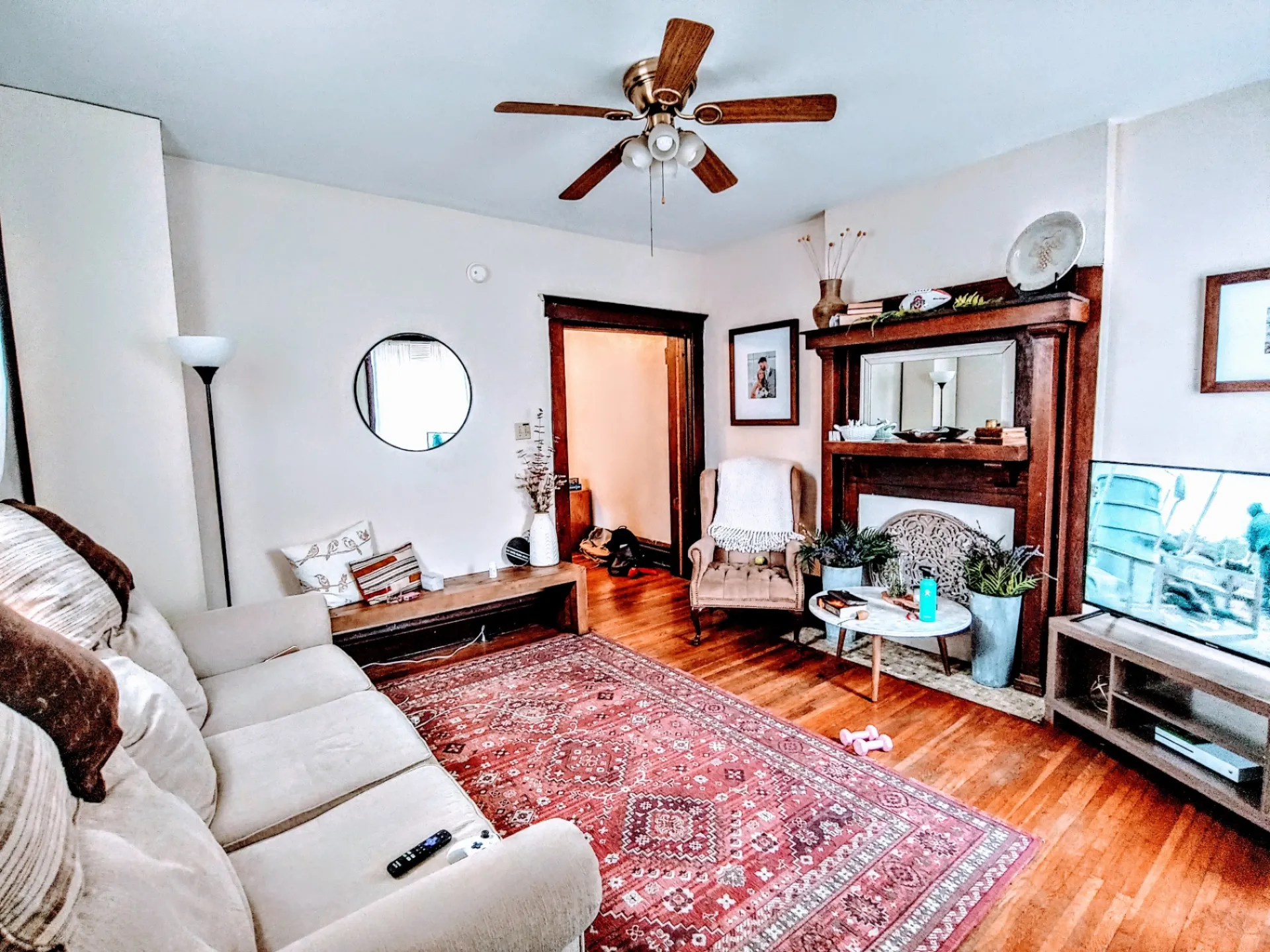 113 W 9th living room with original wood mantel, ceiling fan and refinished hardwood floors