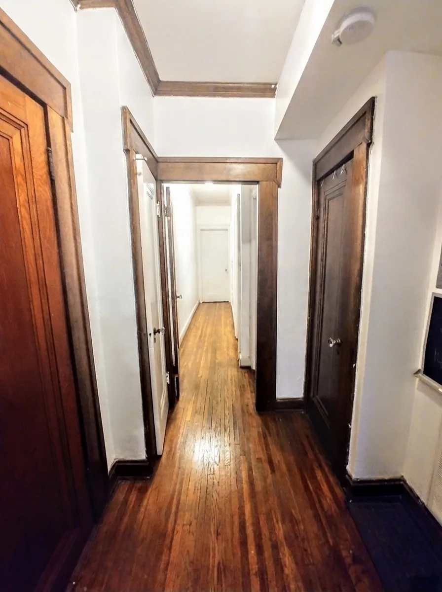 Unit B hallway with dark wood trim and original hardwood floors