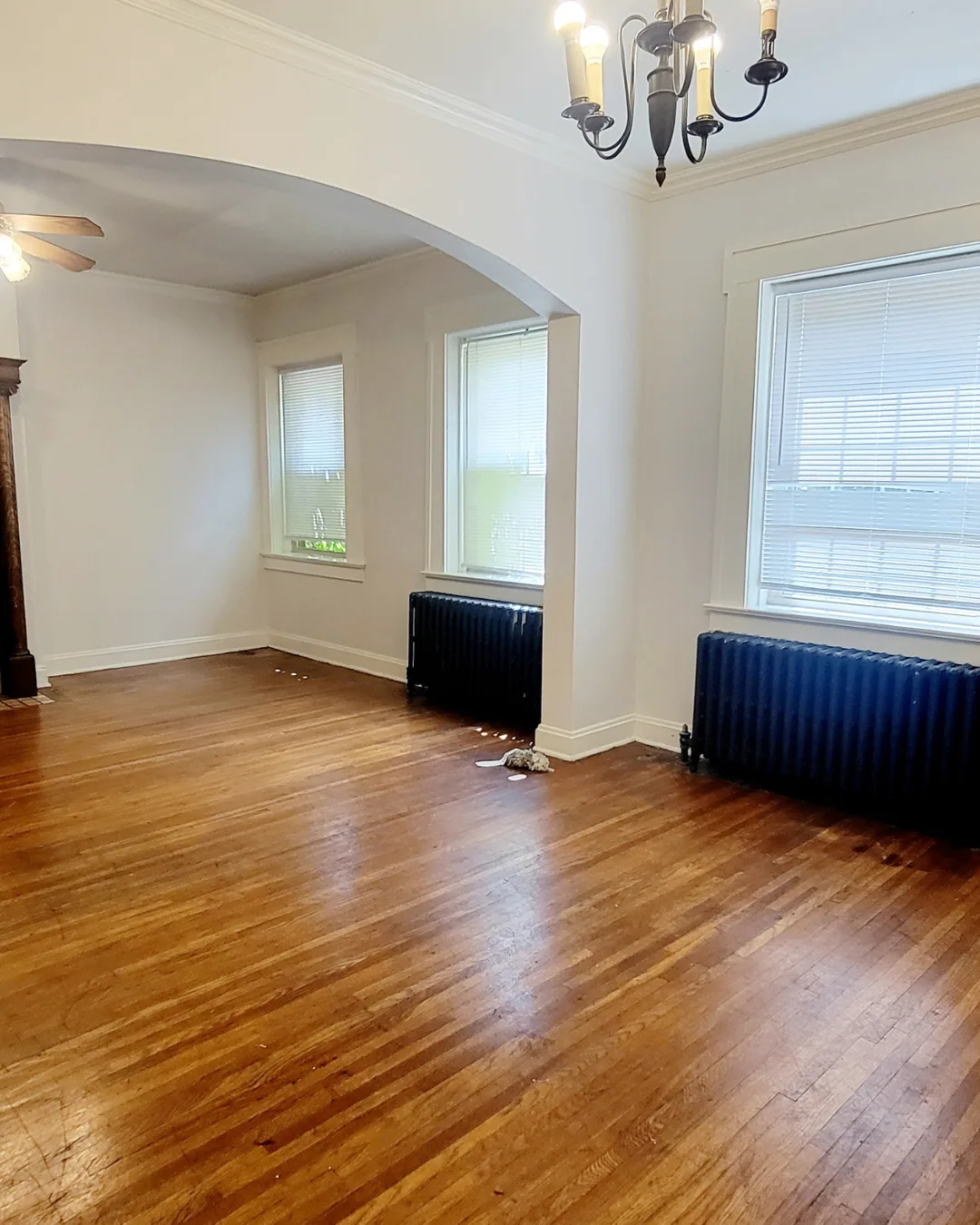 Unit A dining room with chandelier, hardwood floors, and large windows