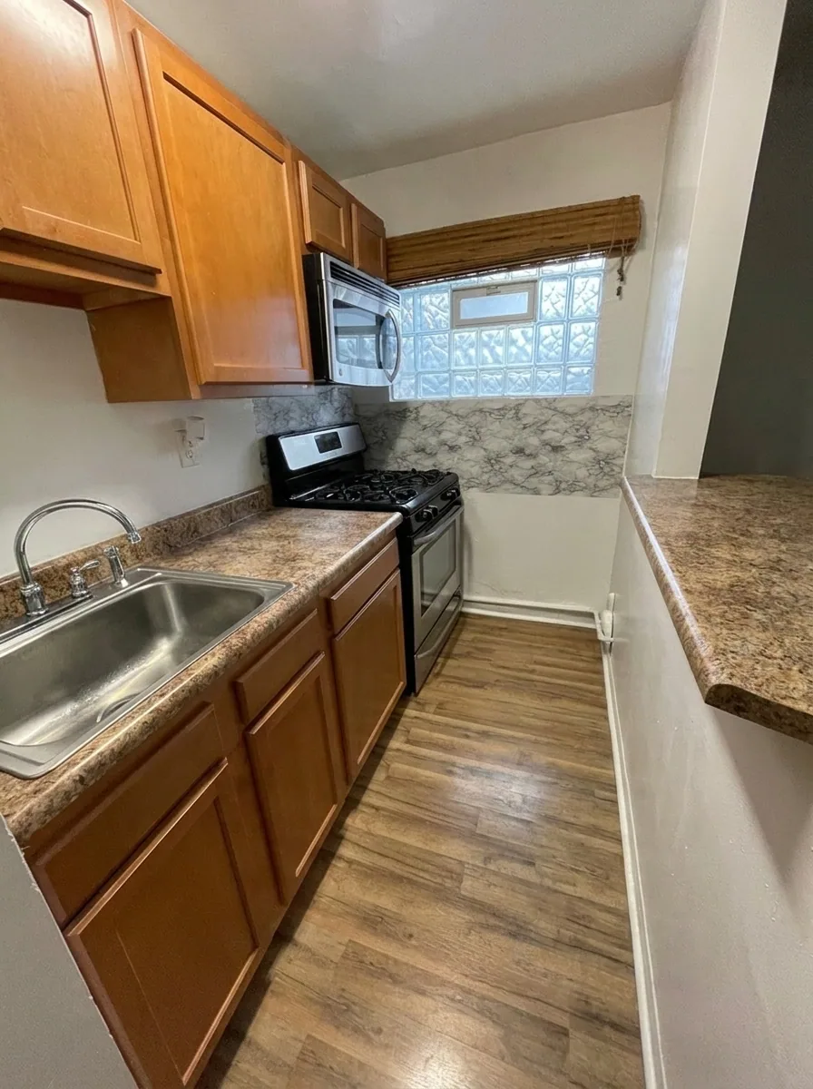 Unit M kitchen with stainless sink, wood cabinets, and plank flooring