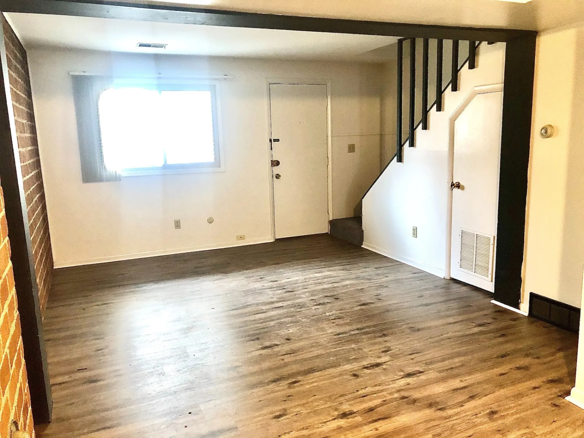 2011 Summit St. Unit F lower-level bonus room with fresh carpet, brick accent, and understair storage
