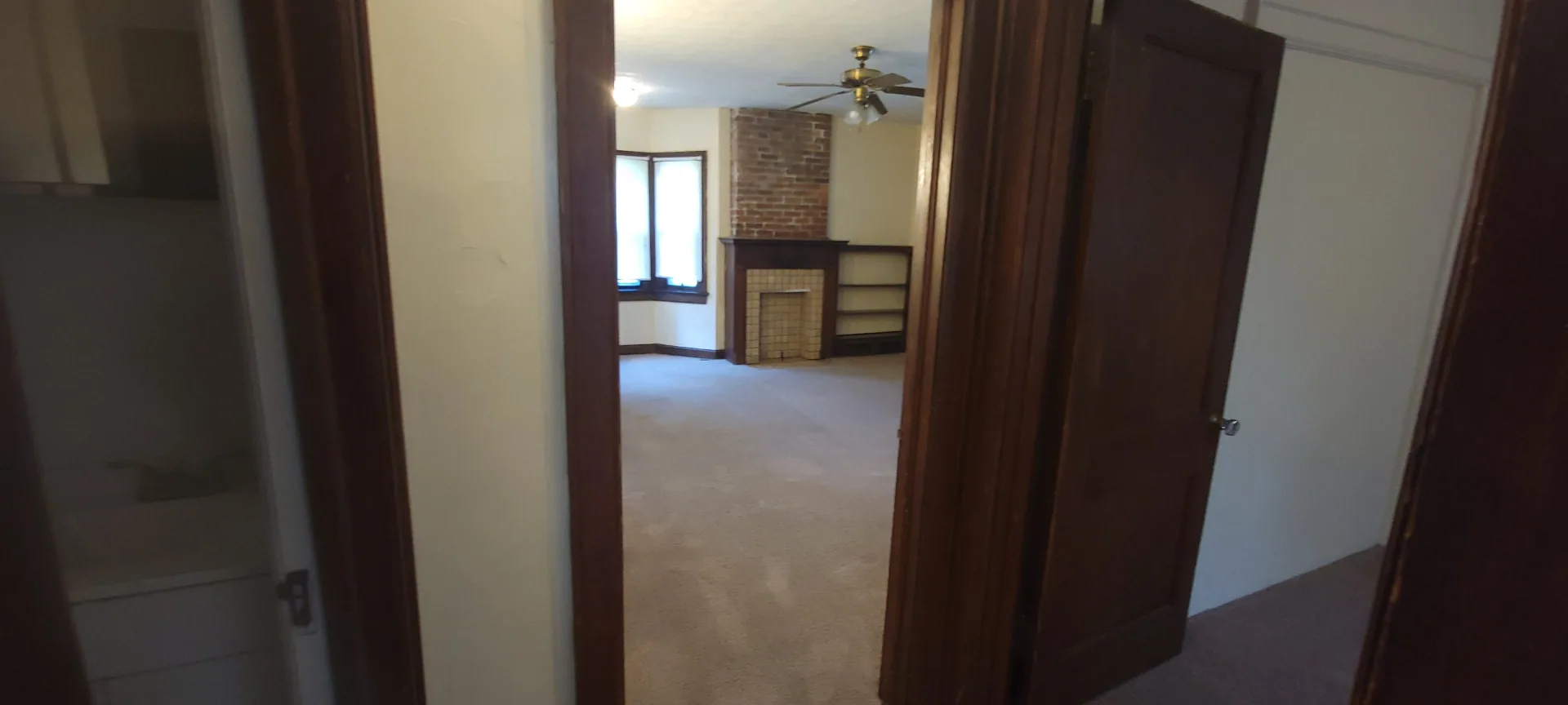 2054 Iuka Ave. C view from hallway into living room showing brick fireplace and built-in shelving
