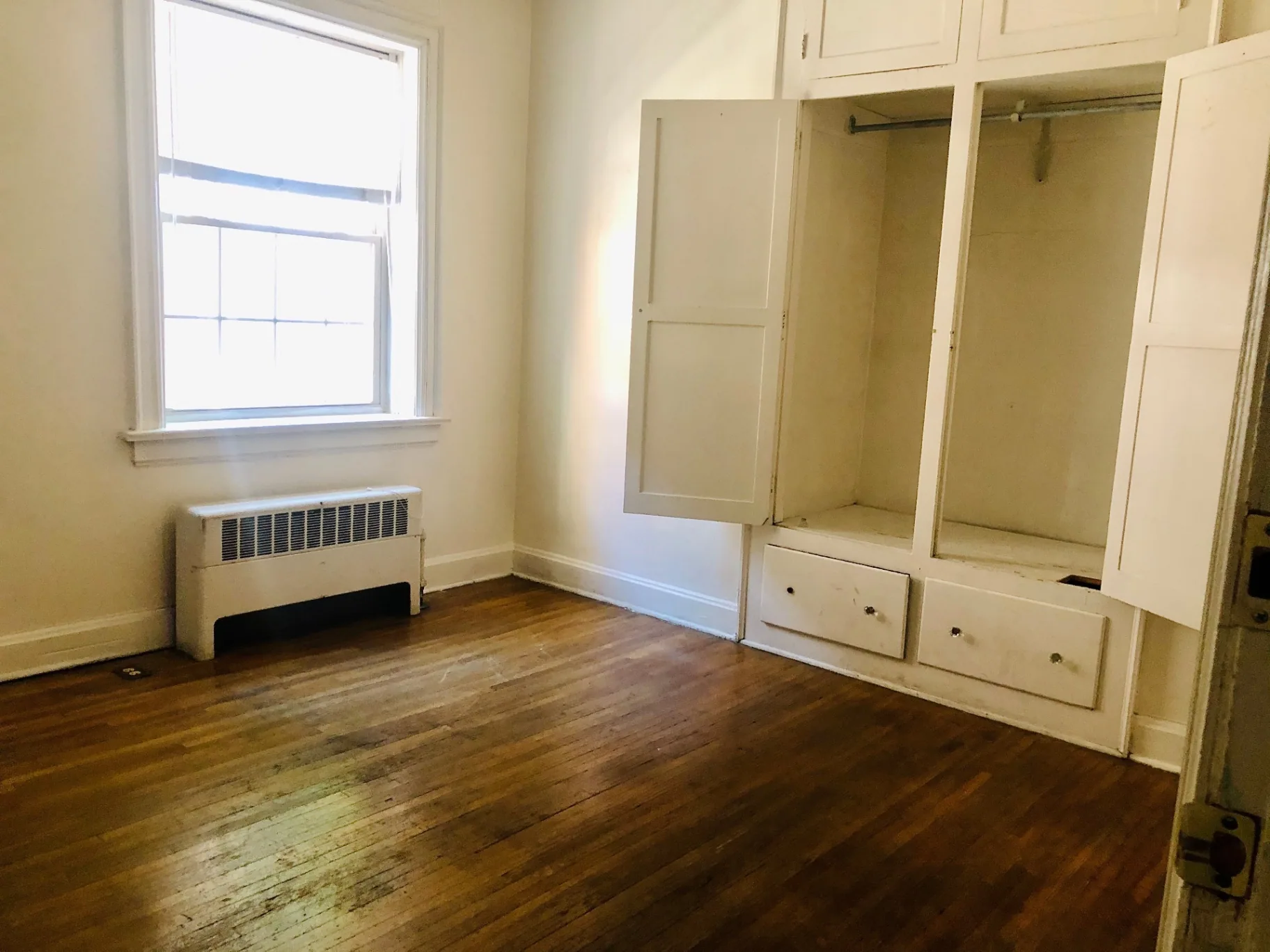 Unit G bedroom with hardwood floors and built-in wardrobe with drawers