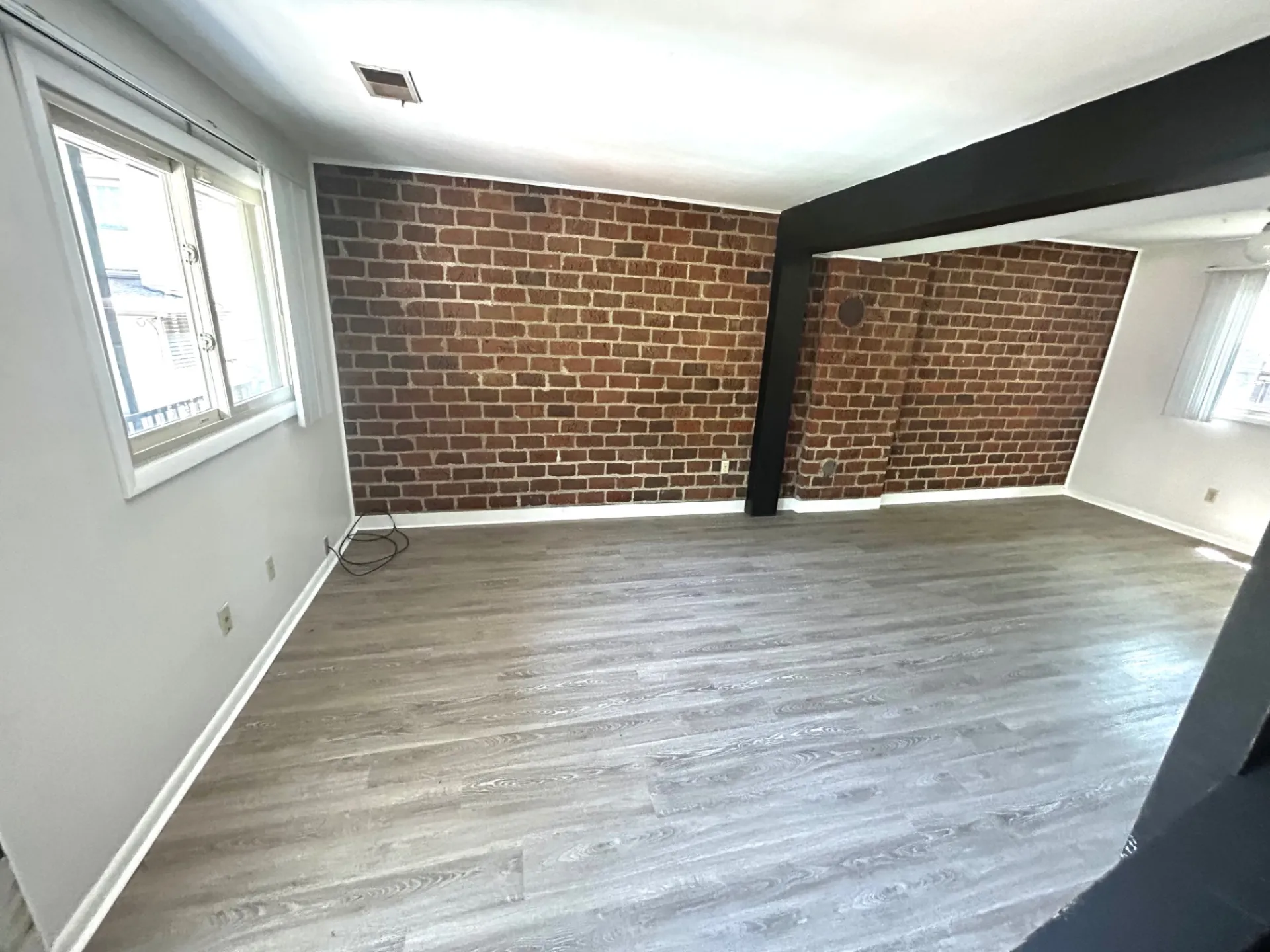 2011 Summit St. Unit E living room with bright corner window and exposed brick accent walls