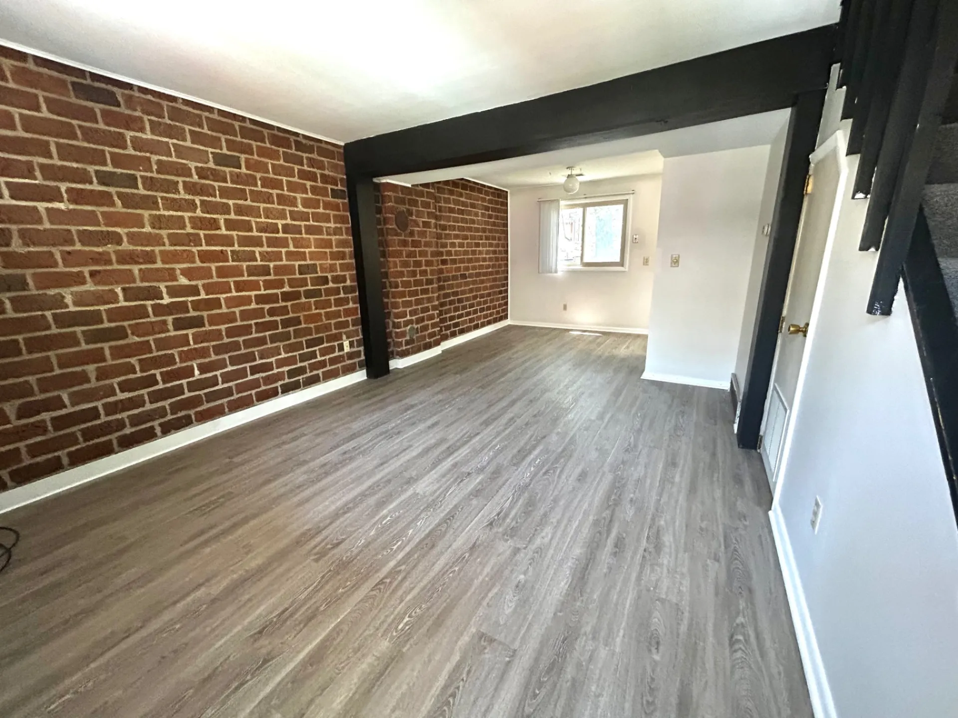 2011 Summit St. Unit E wide living/dining area with double brick accent walls and dark plank floors