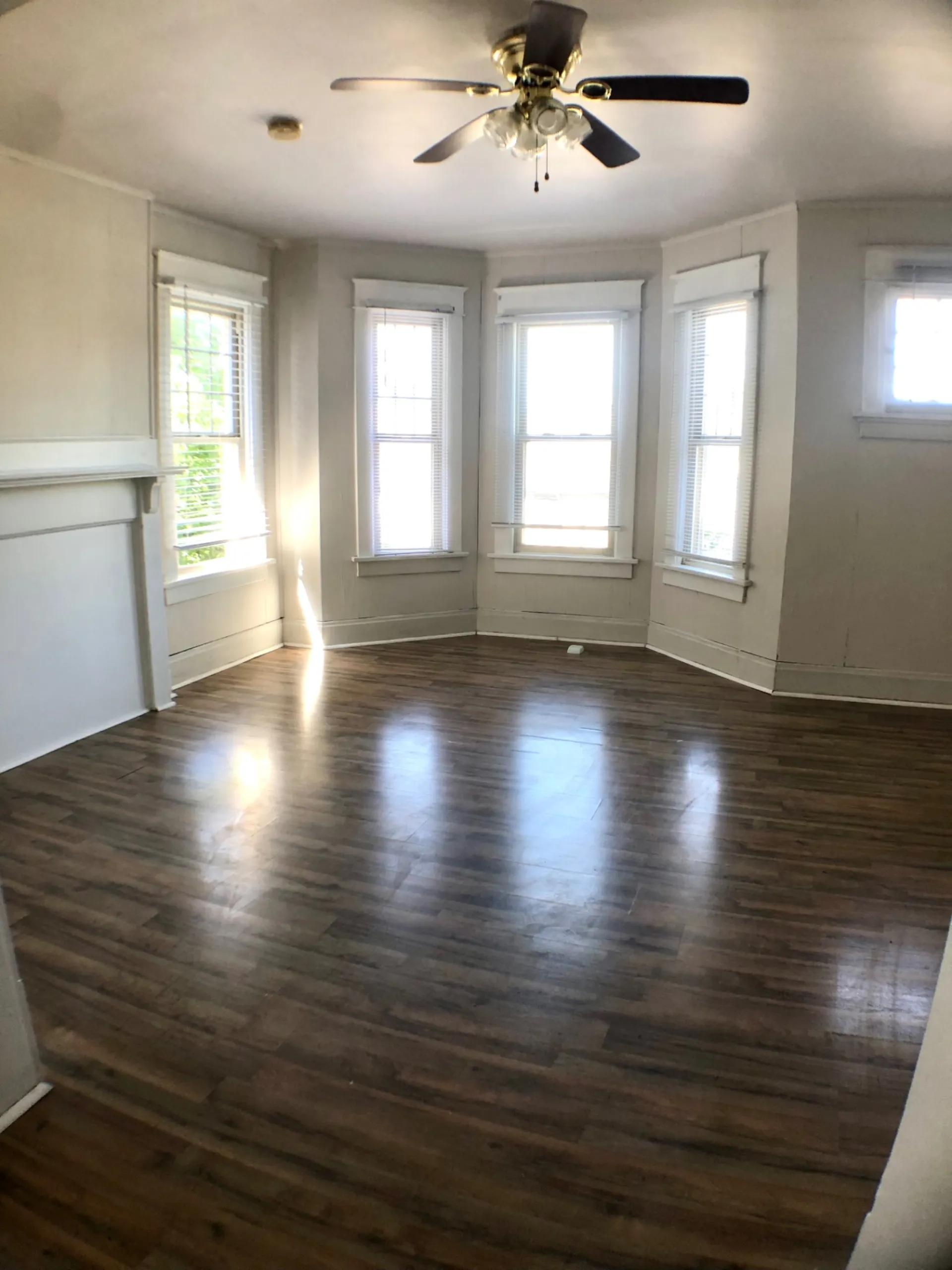 1814 Summit St. bright bay-window living room with ceiling fan, decorative mantel, and hardwood floors