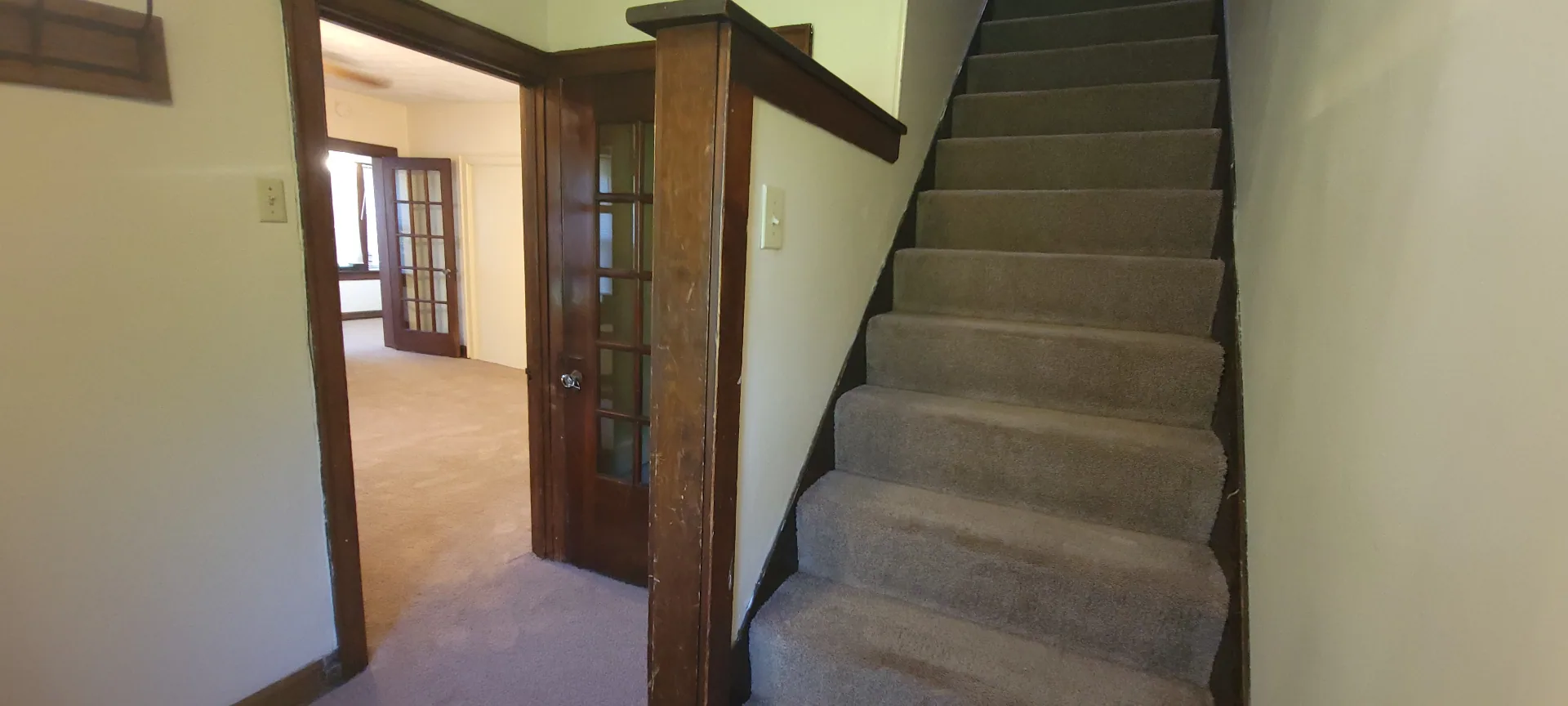2054 Iuka Ave. C carpeted staircase leading to the second floor with original wood newel post
