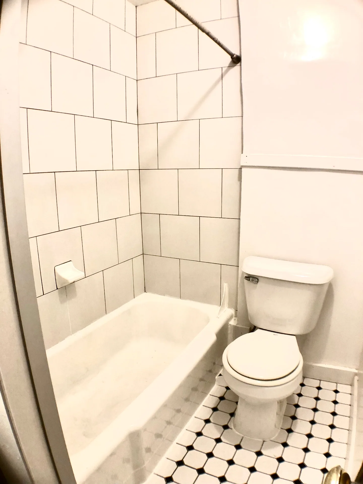 2054 Iuka Ave. D bathroom with large-format white subway tile tub surround and vintage black-and-white hex tile floor