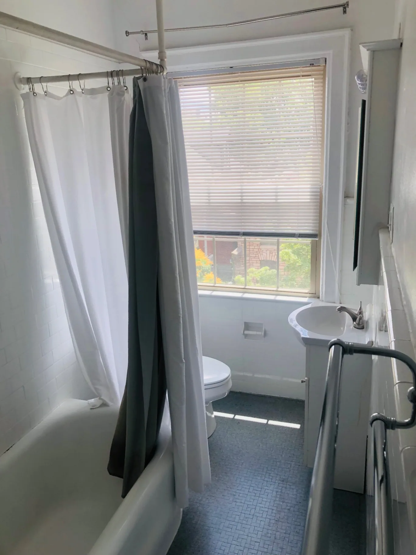 Unit K bathroom with clawfoot tub, pedestal sink, and large window