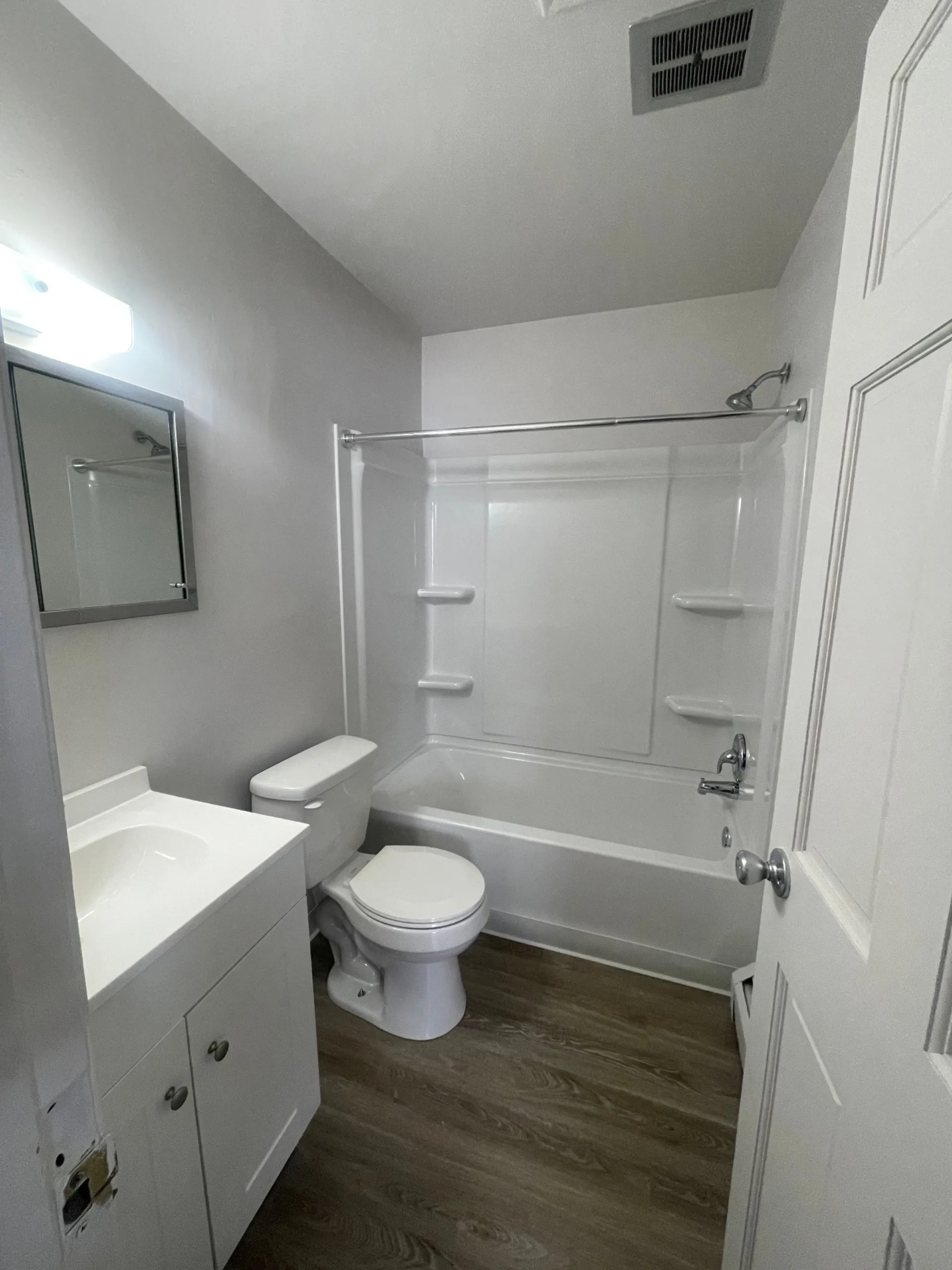 1827 N 4th St. Unit 8 bathroom with white vanity, tiled tub surround, and wood-look floor