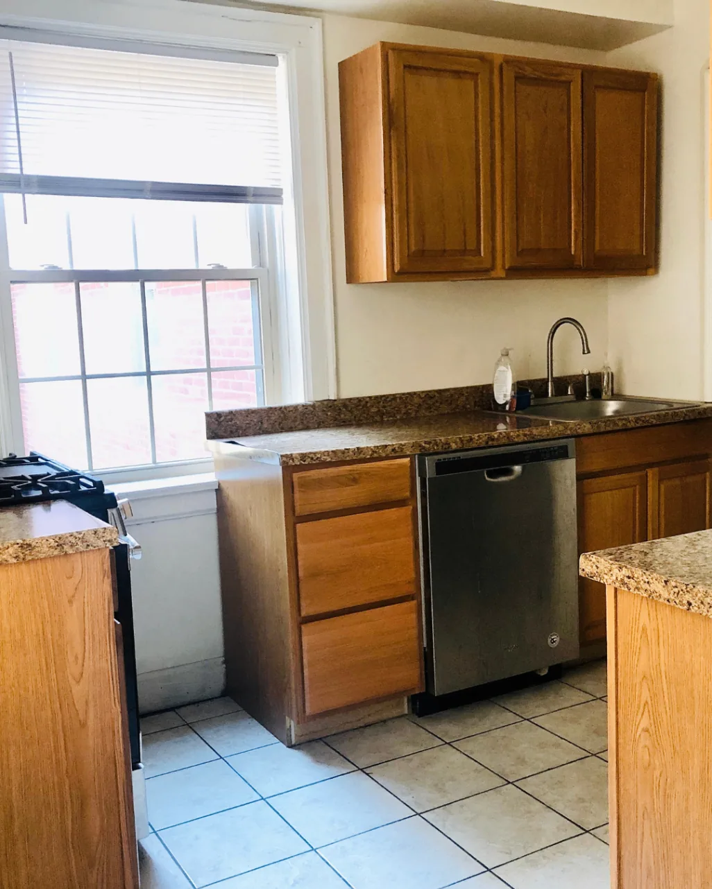 Unit A kitchen with granite countertops, stainless dishwasher, and large window