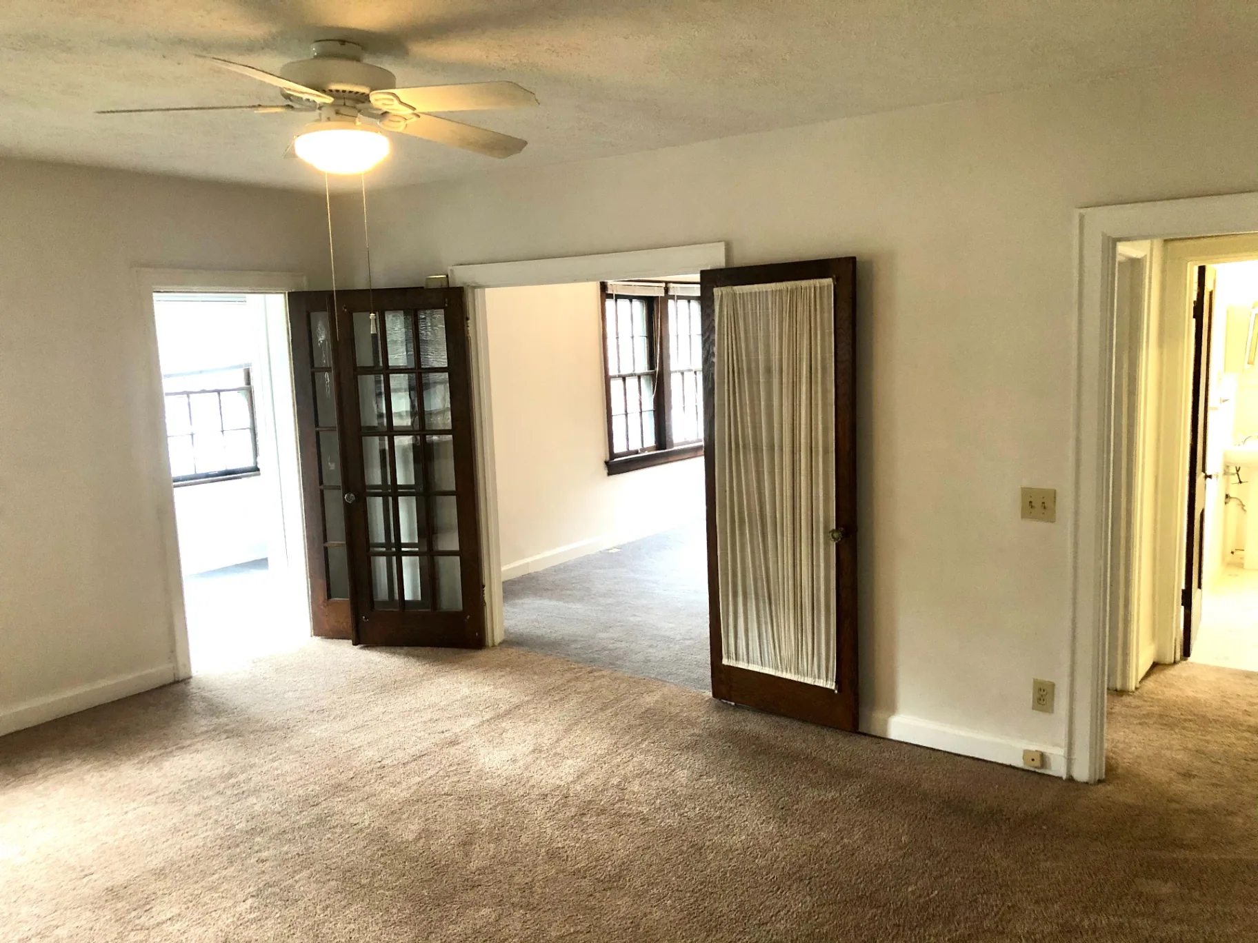 2044 Iuka Ave. B open living space with original French doors and ceiling fan connecting multiple rooms