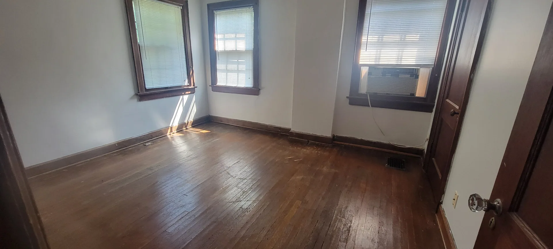2044 Iuka Ave. C spacious bedroom with three windows, hardwood floors, and window AC