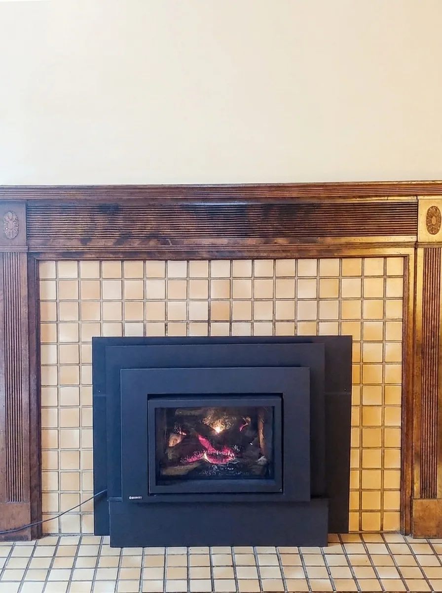 Close-up of Unit C gas insert fireplace with tile surround and wood mantel