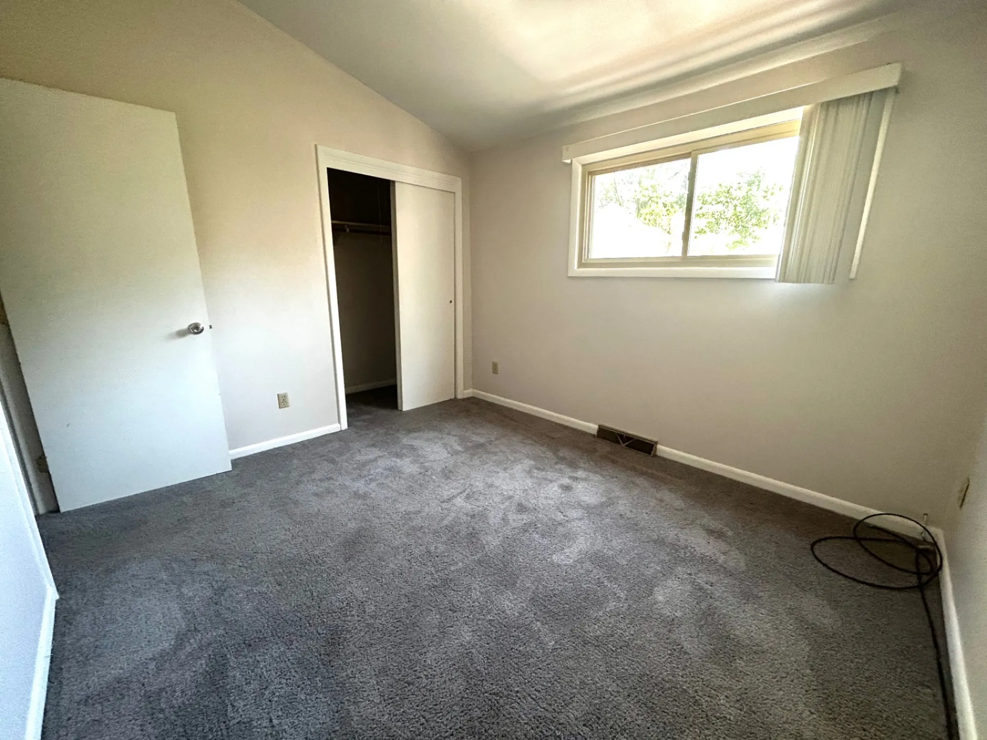 2011 Summit St. Unit E first bedroom with window, open closet, and gray carpet