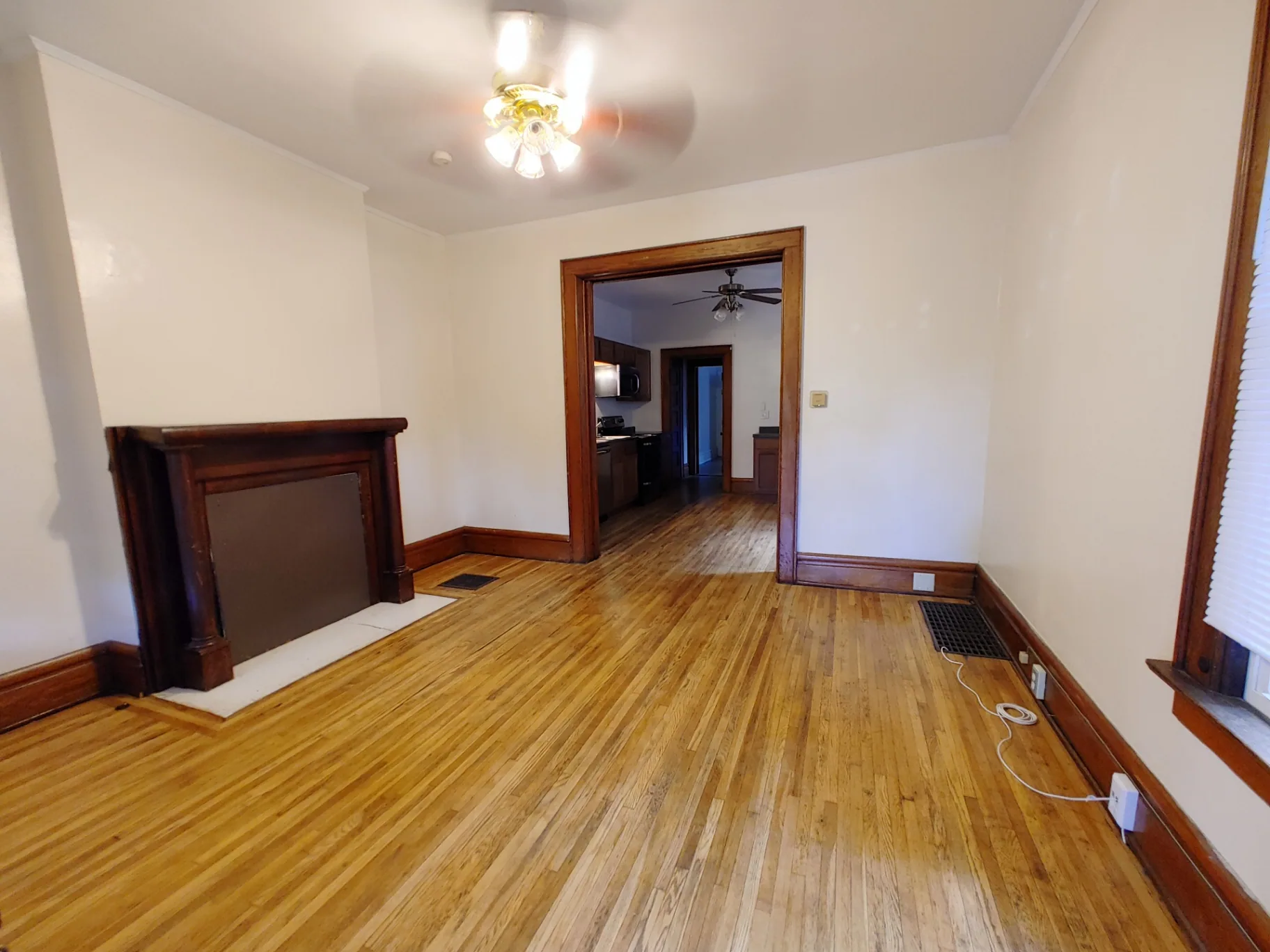 374 A E 14th Ave. living room with original wood mantel, hardwood floors, and passthrough to kitchen