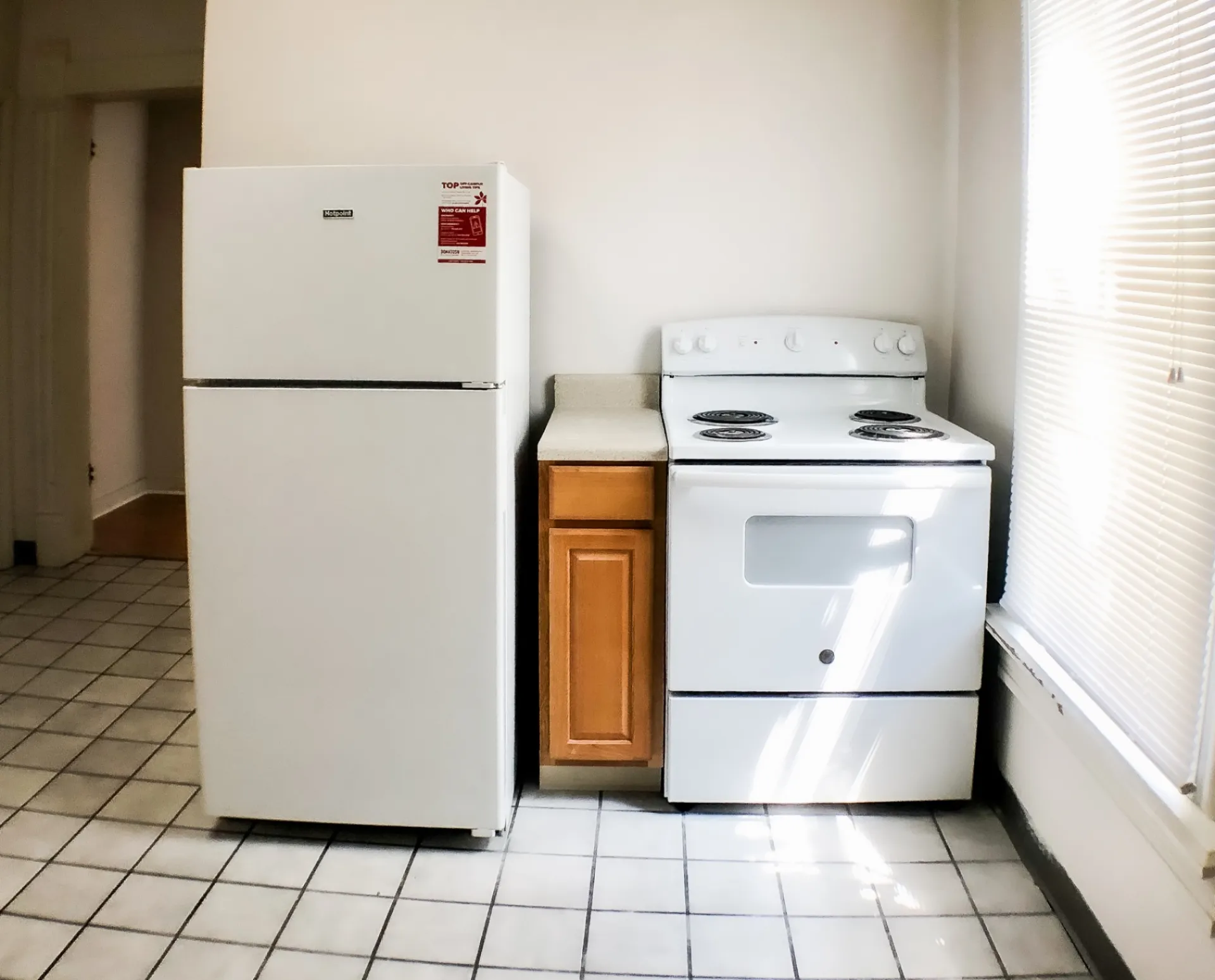 Unit A kitchen appliances — fridge and electric range next to bright window