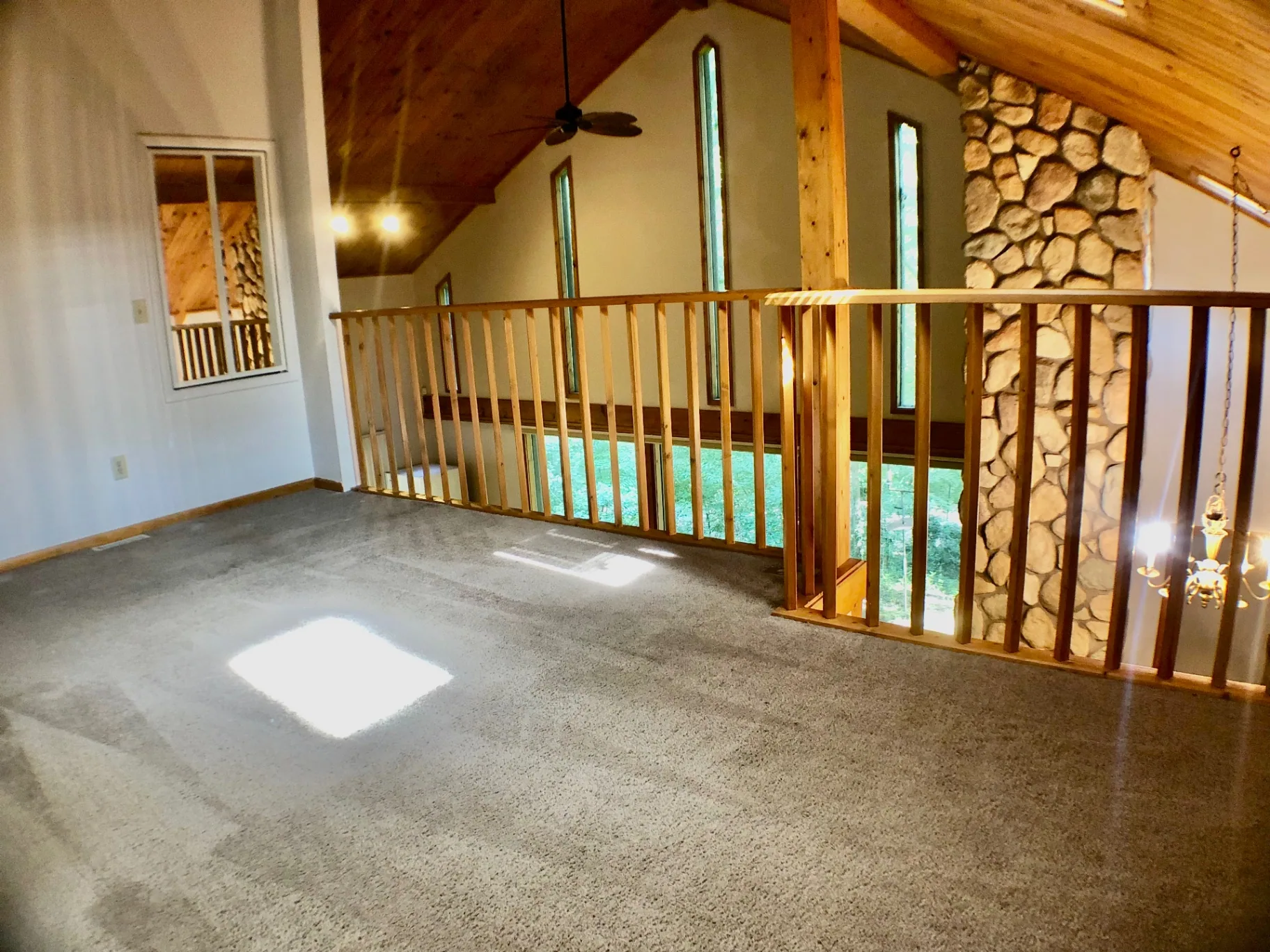 2040 Iuka Ave House upstairs loft with tall windows, stone chimney, and vaulted wood ceiling