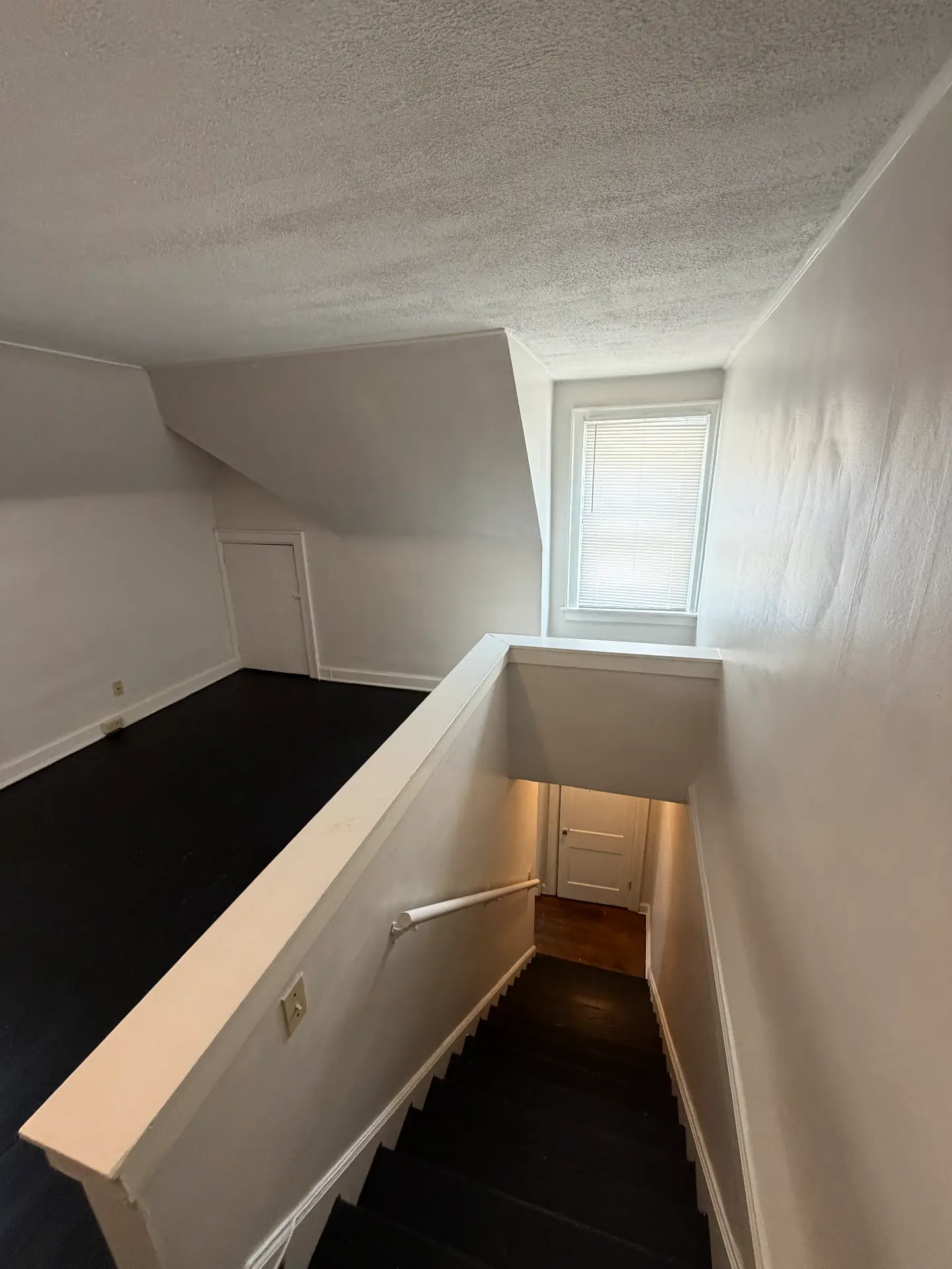 2048 Iuka Ave. D upper landing with window, painted black stairs, and handrail down to the entry