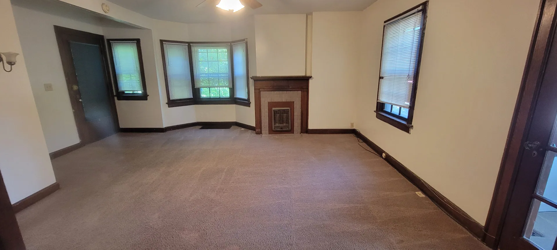2054 Iuka Ave. A living room with original tile fireplace, wood mantel, and bay window