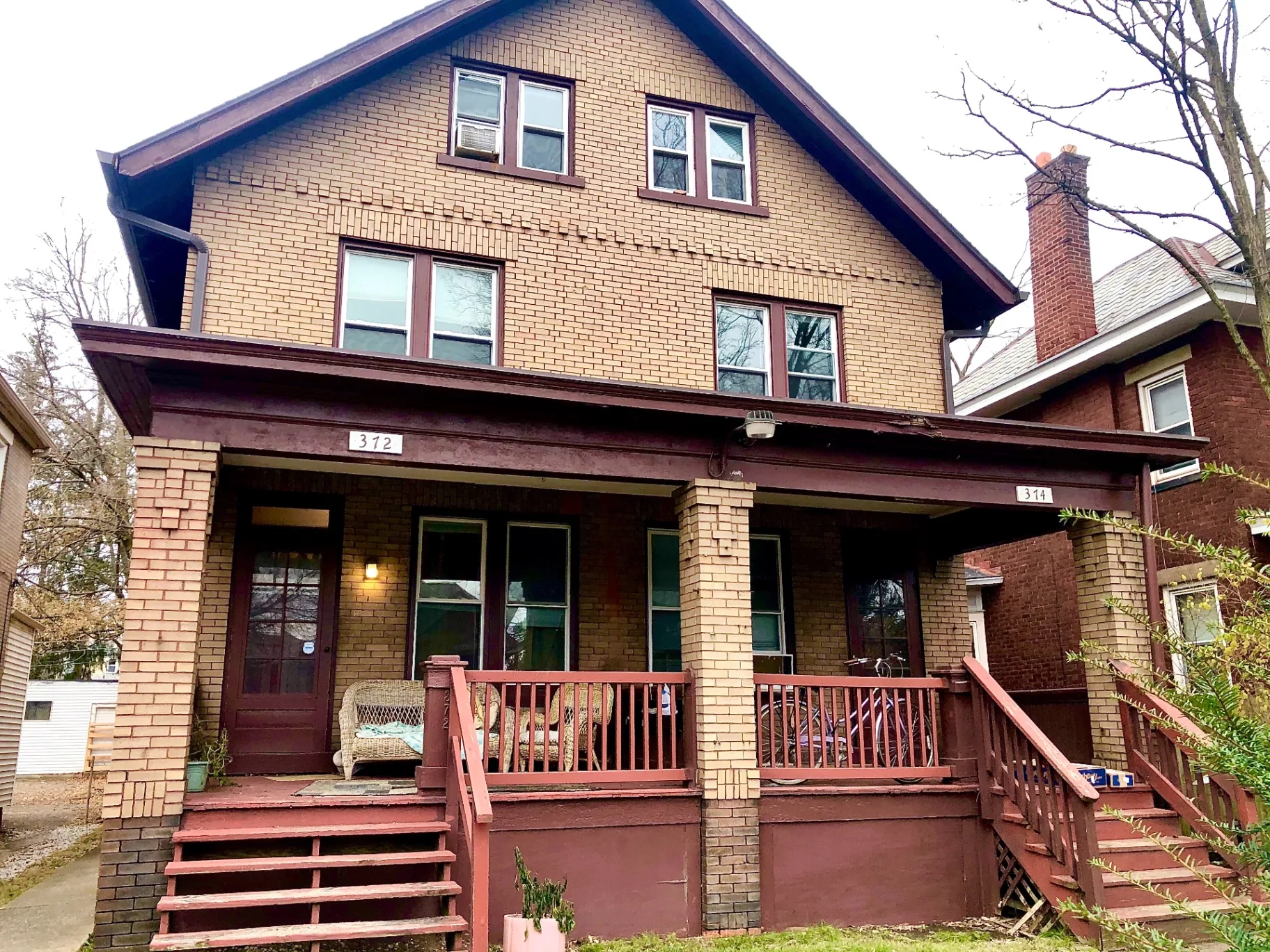374 B E 14th Ave. brick two-story house exterior with covered front porch, wicker seating, and red-painted steps