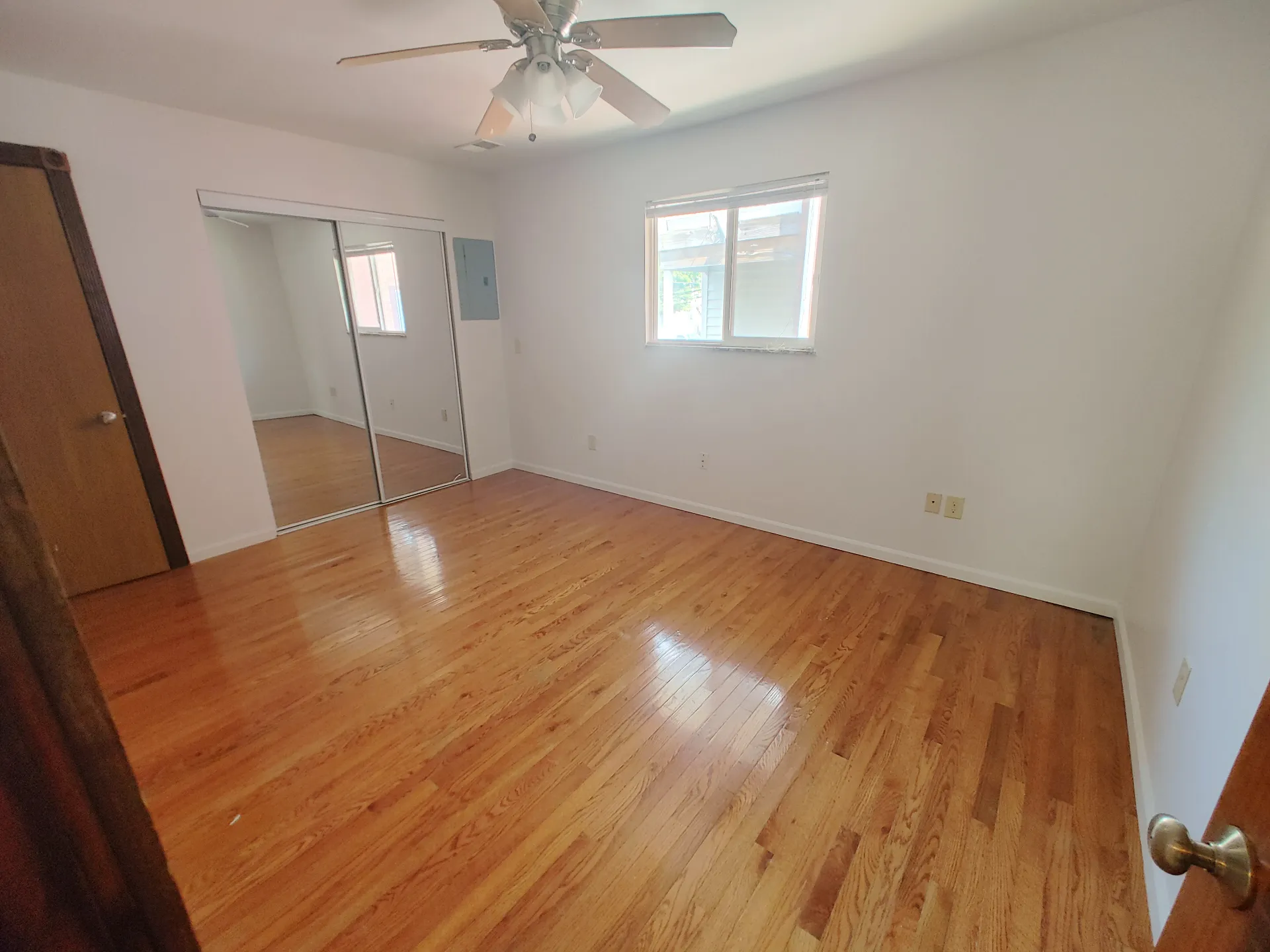 1827 N 4th St. Unit 6 bright bedroom with hardwood floors, mirrored closet doors, and ceiling fan