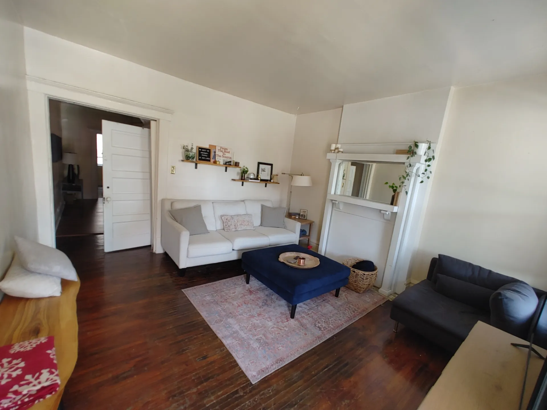 117 W 9th staged living room with hardwood floors, white sofa and original mantel