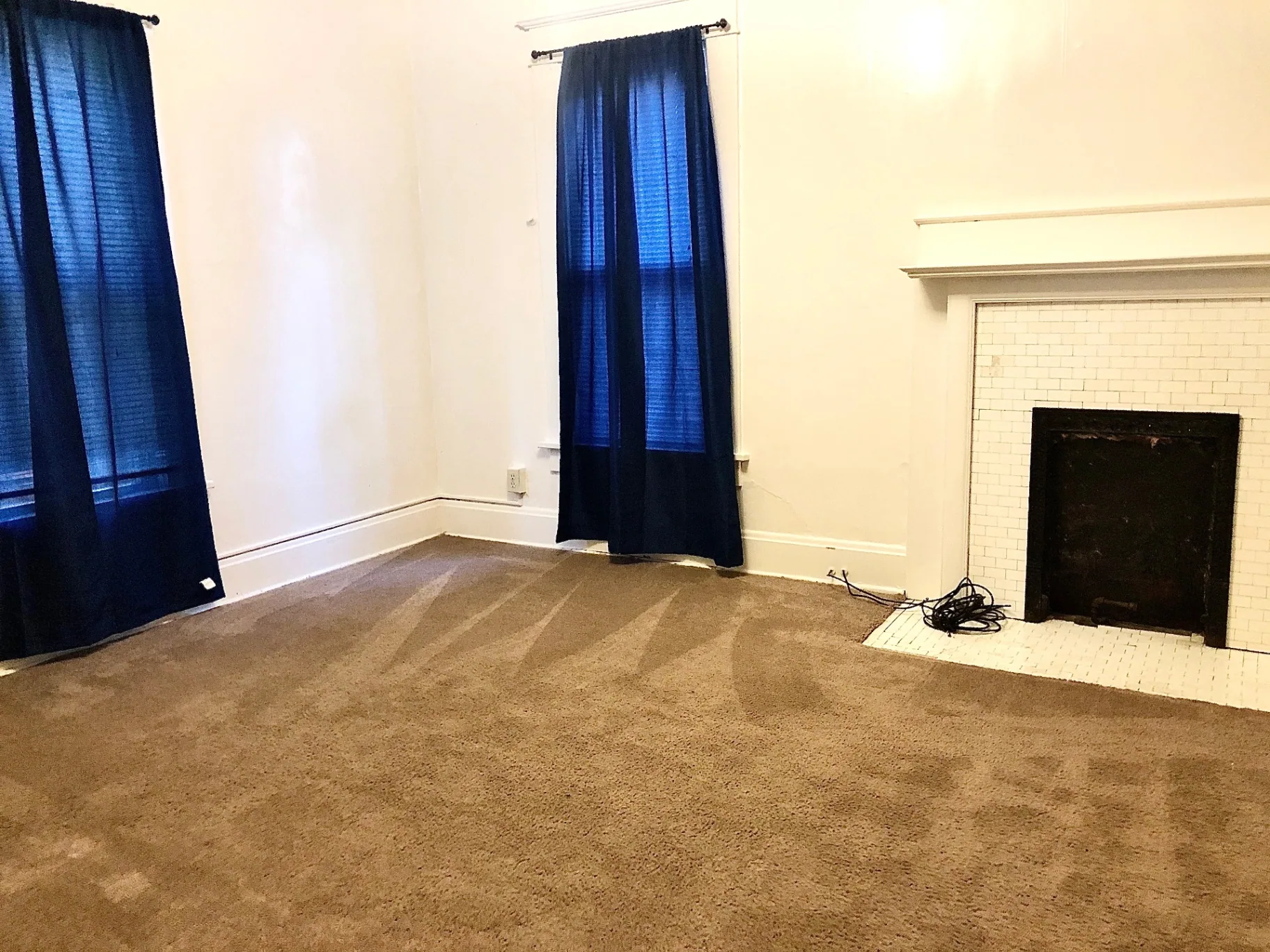 2015 Summit St. living room with white subway tile fireplace, blue curtains, and carpet