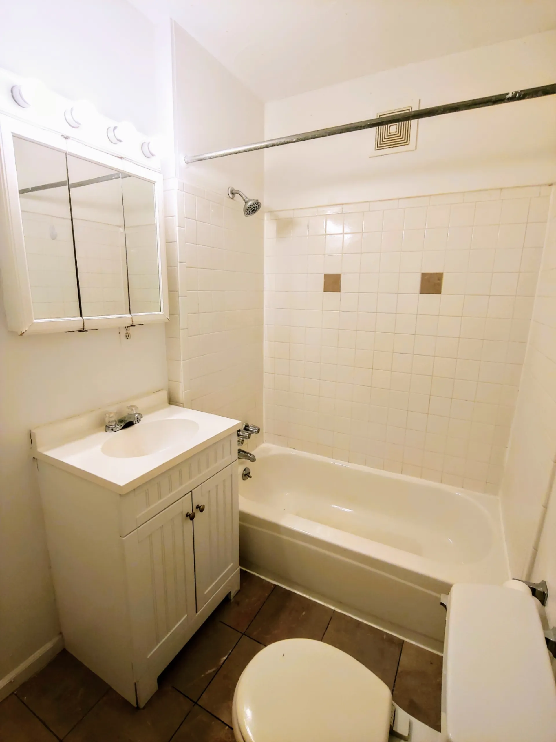 1818 Summit St. second bathroom with white tile tub surround, vanity, and mirrored medicine cabinet