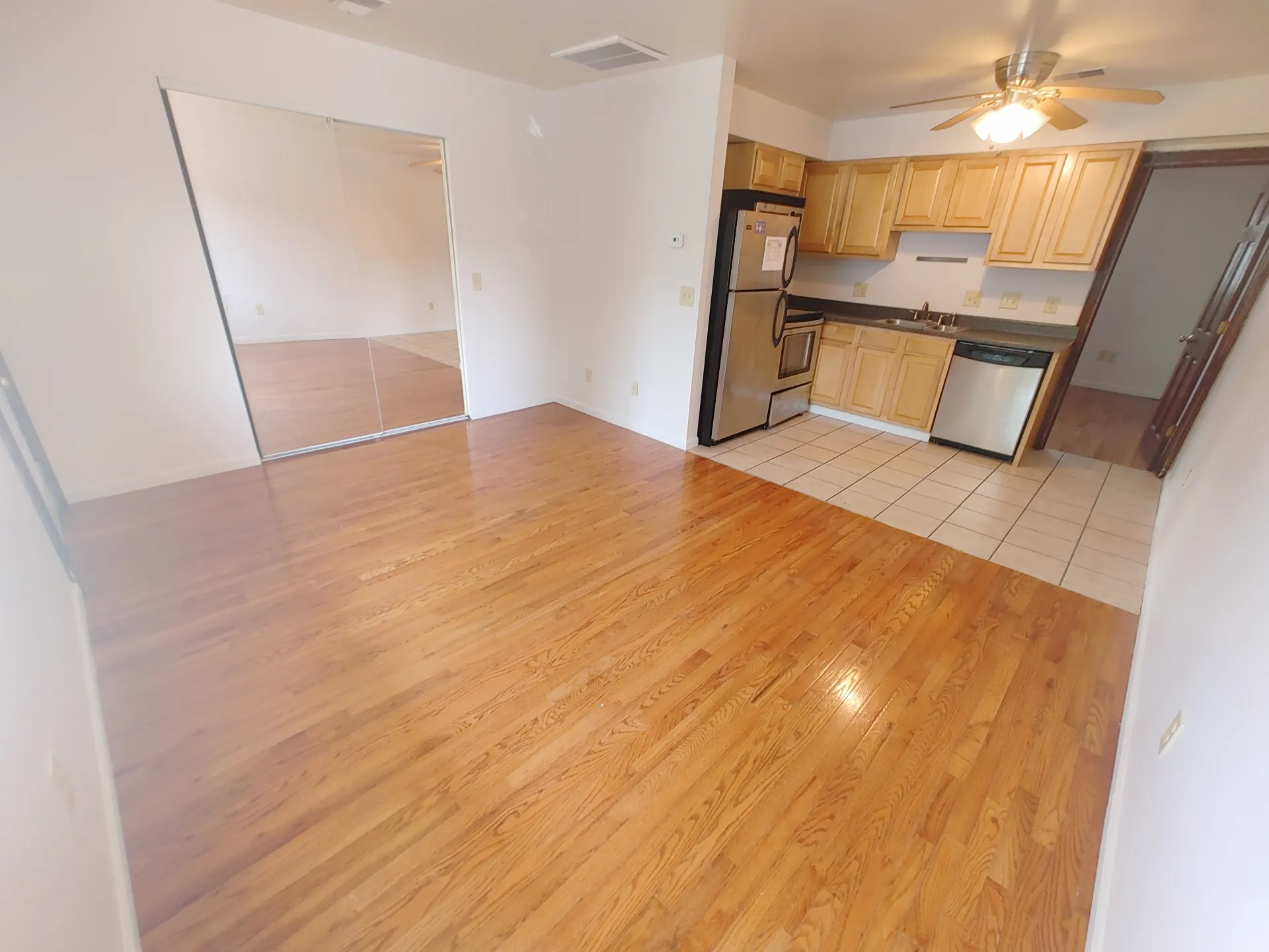 1827 N 4th St. Unit 6 open living area with hardwood floors, mirrored closet doors, and adjacent kitchen with stainless appliances
