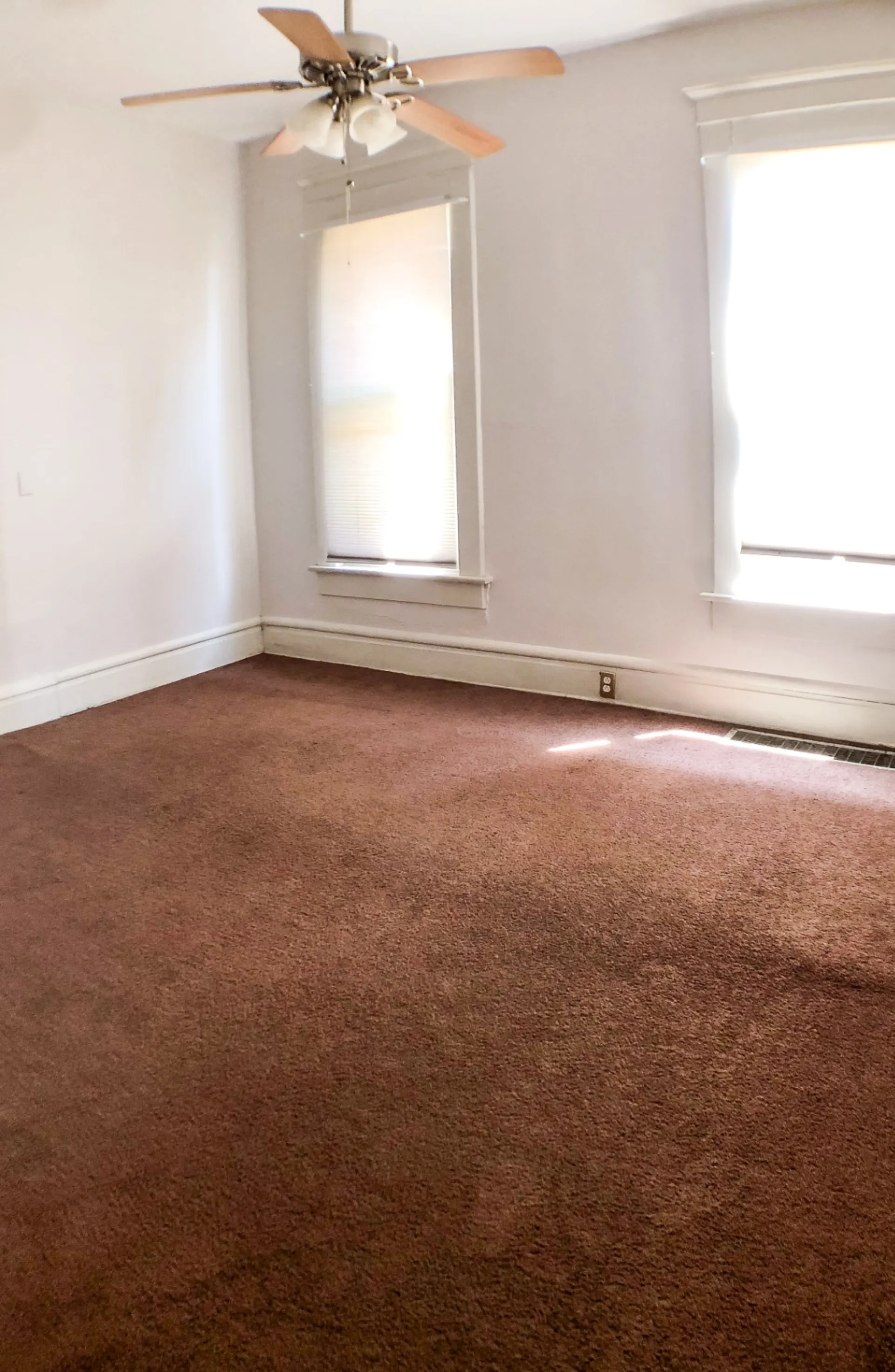 Unit A primary bedroom with ceiling fan, dual windows and plush carpet