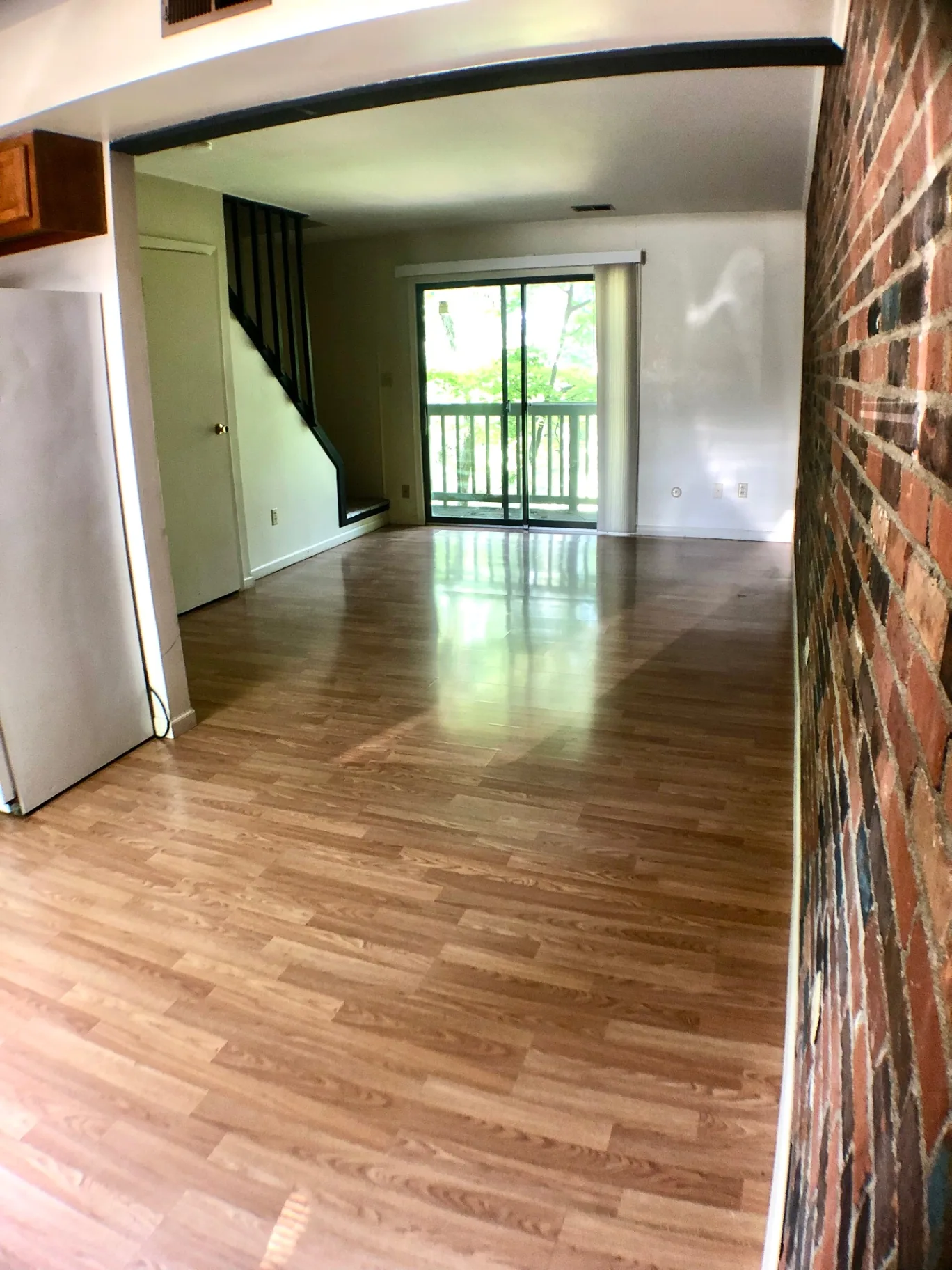 2018 Iuka Ave. long living space with exposed brick wall, wood-look floors, and sliding doors to the balcony
