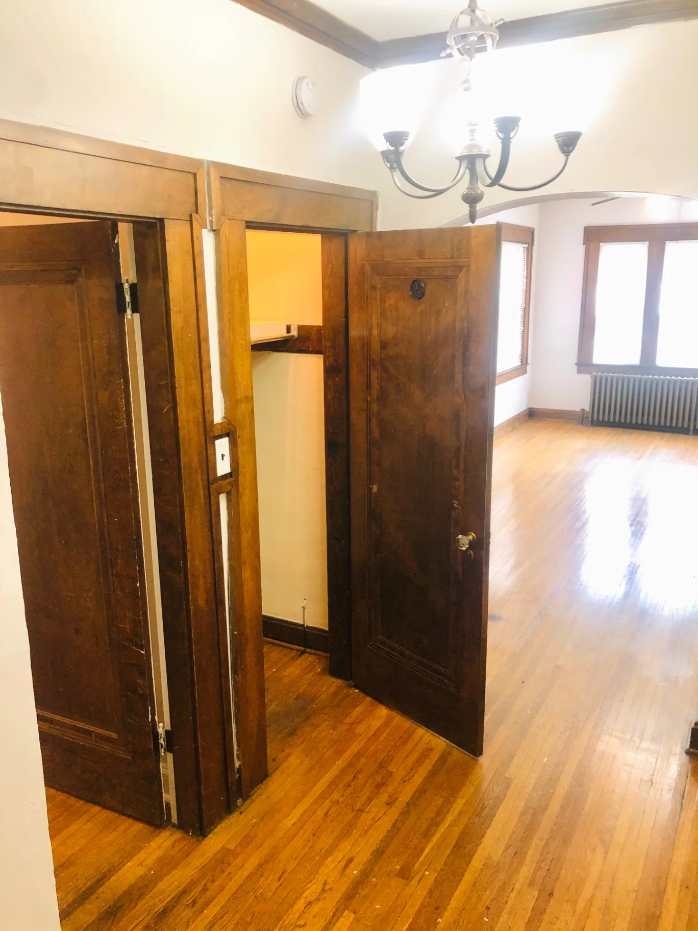 Unit L dining area with chandelier, original woodwork, and archway to living room