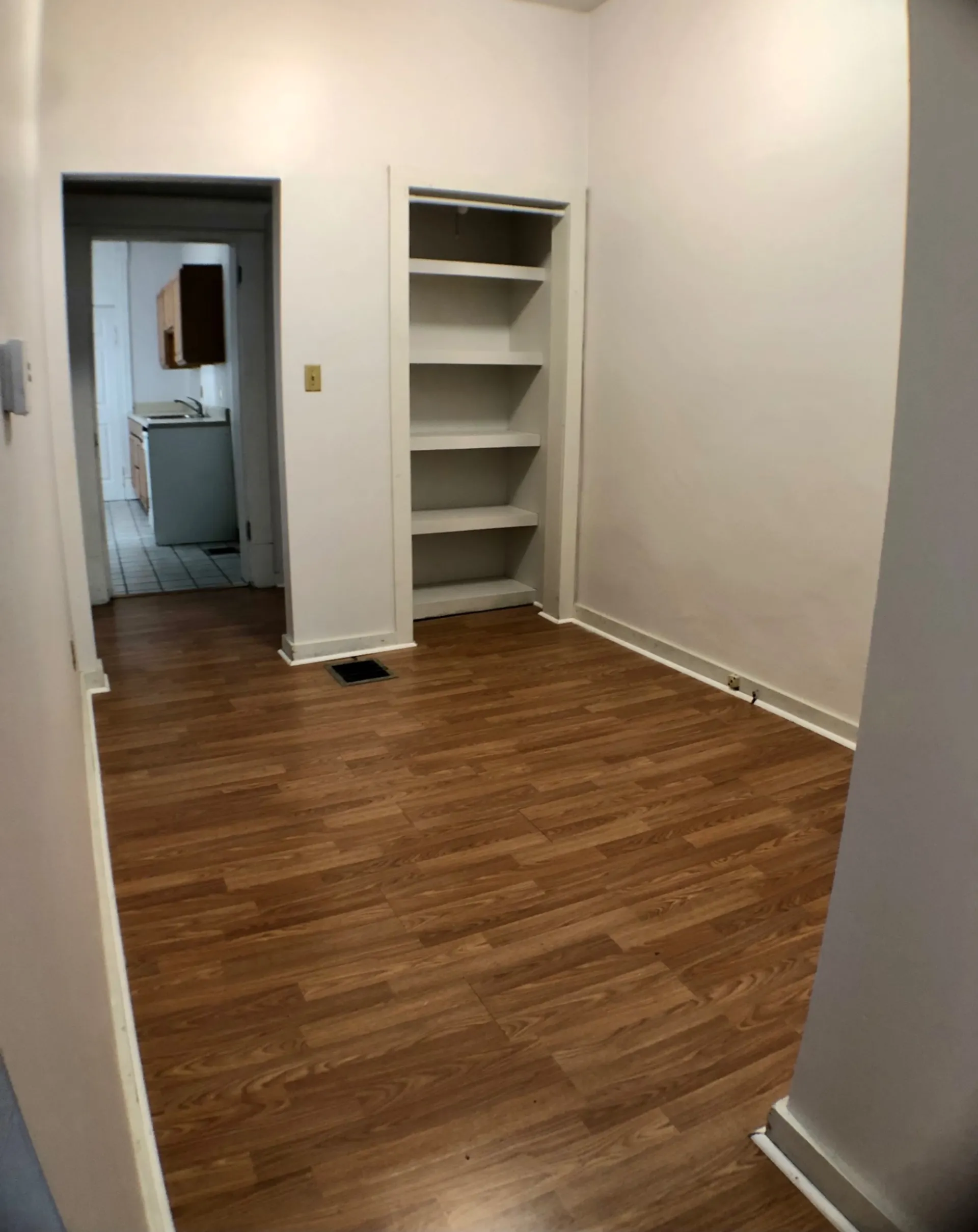 Unit A bedroom with built-in shelving closet and hardwood floors