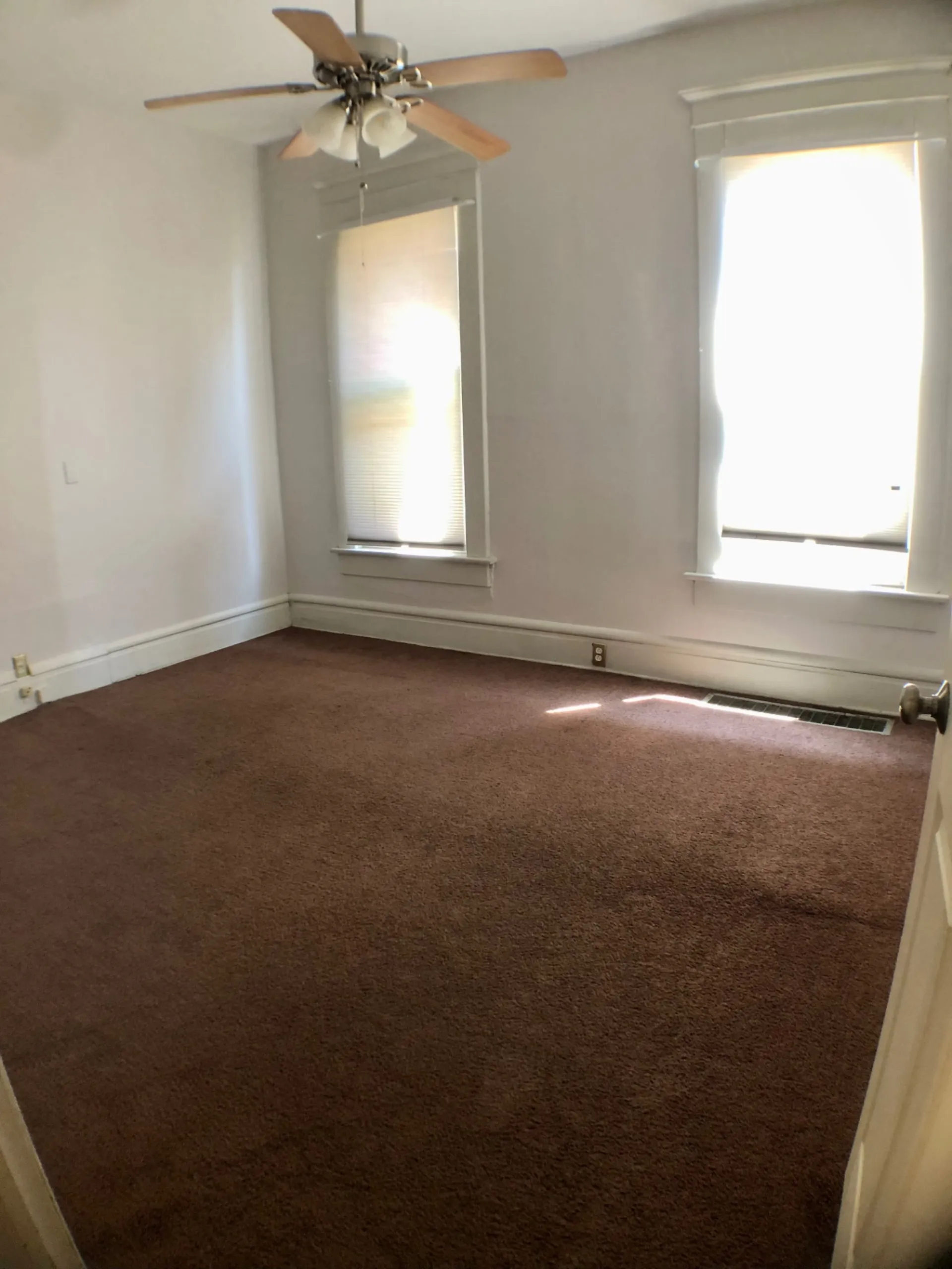 Unit A carpeted bedroom with ceiling fan and two tall windows