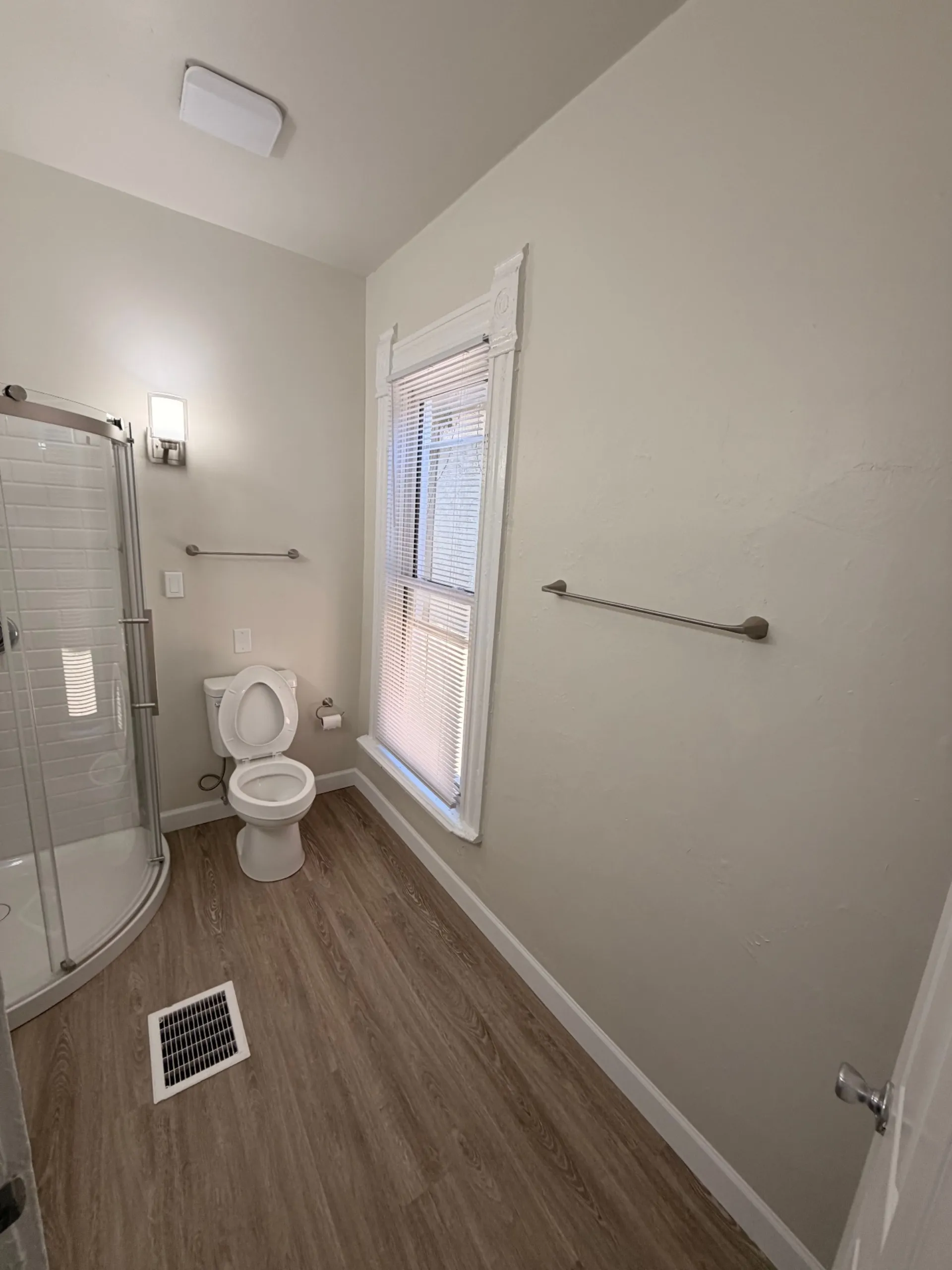 133½ bathroom with plank flooring, glass shower and bright window