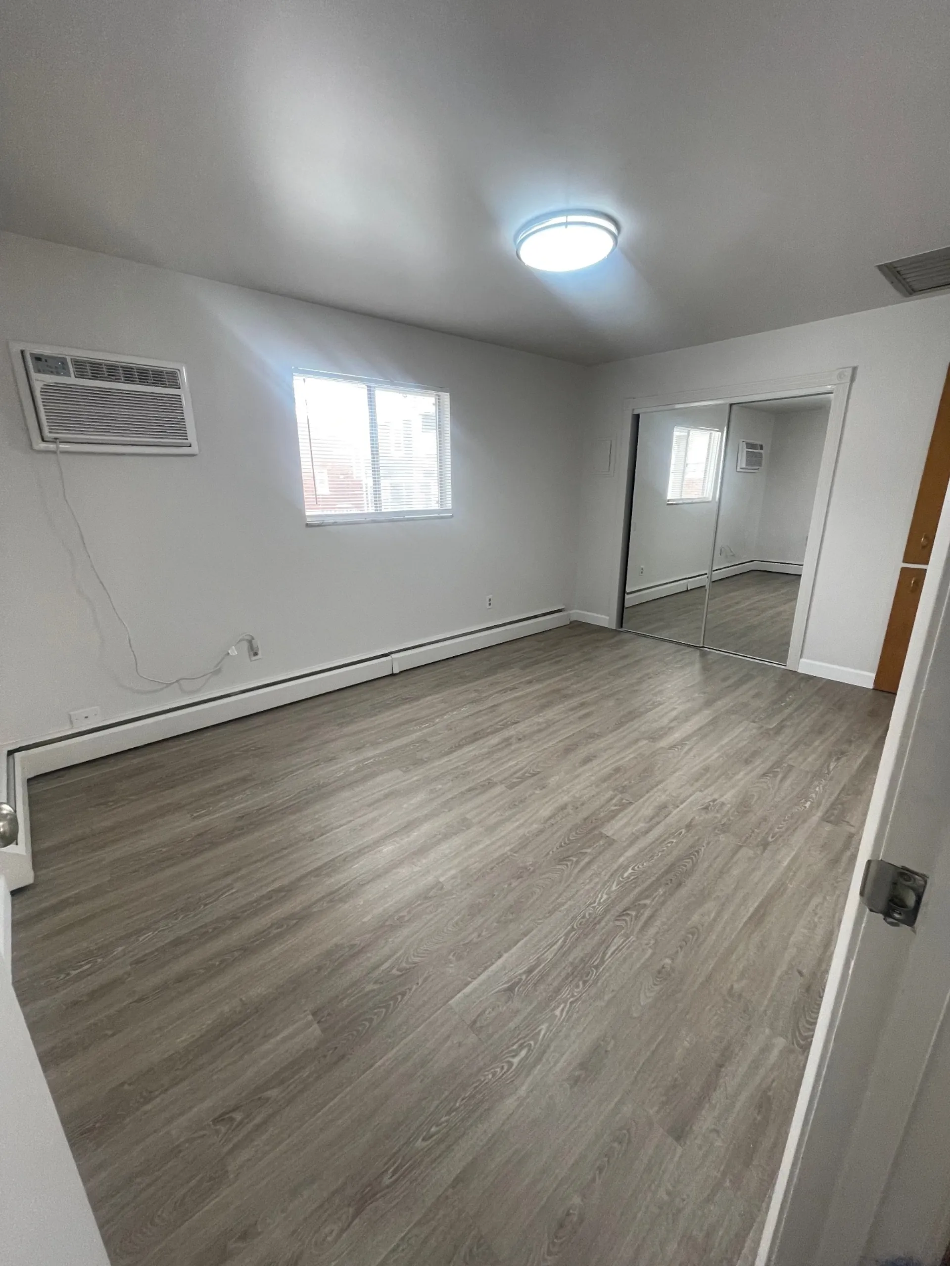 1827 N 4th St. Unit 8 second bedroom with bright window, wall AC, and mirrored closet