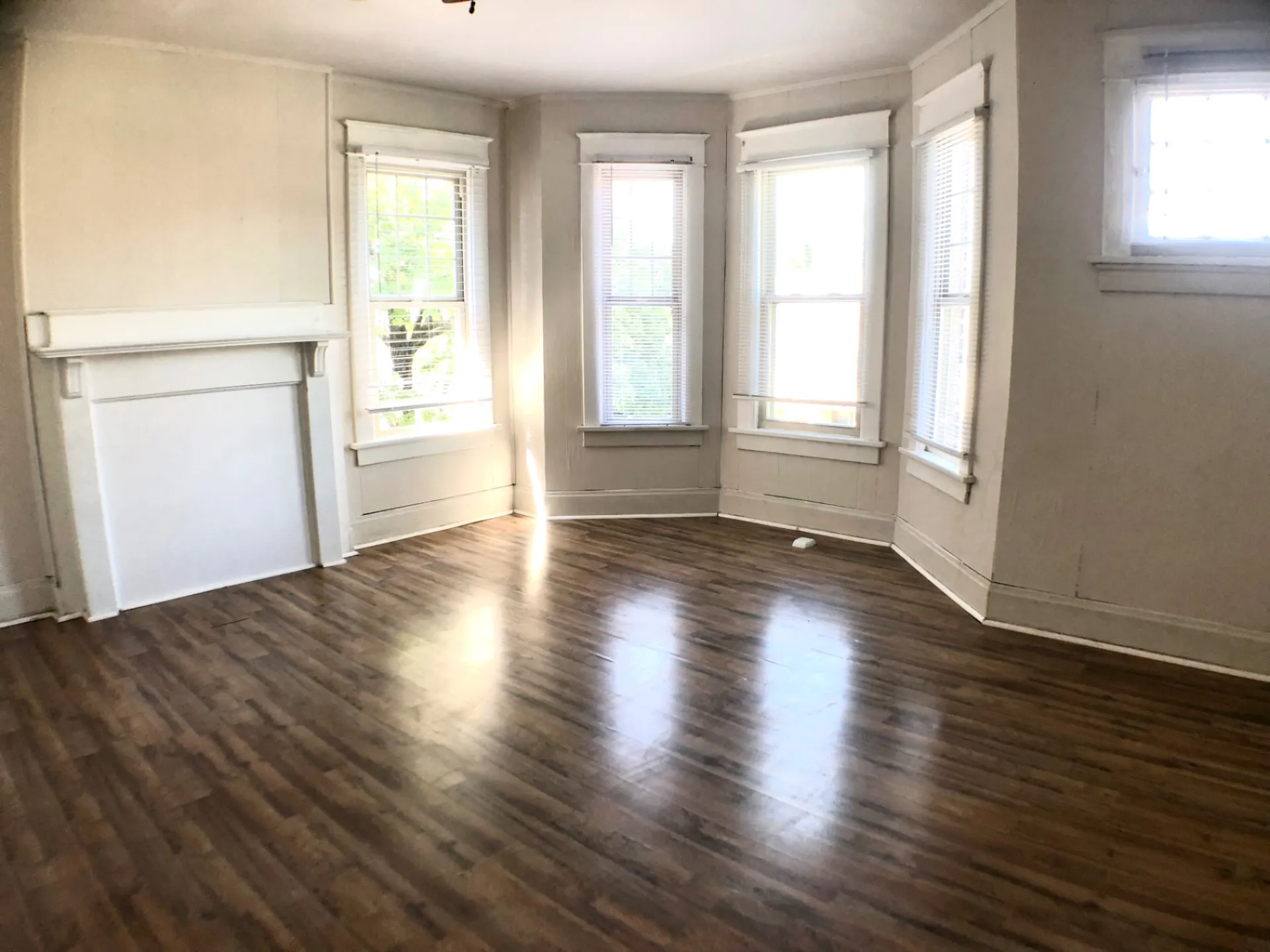 1814 Summit St. spacious living room with white mantel and rounded bay windows