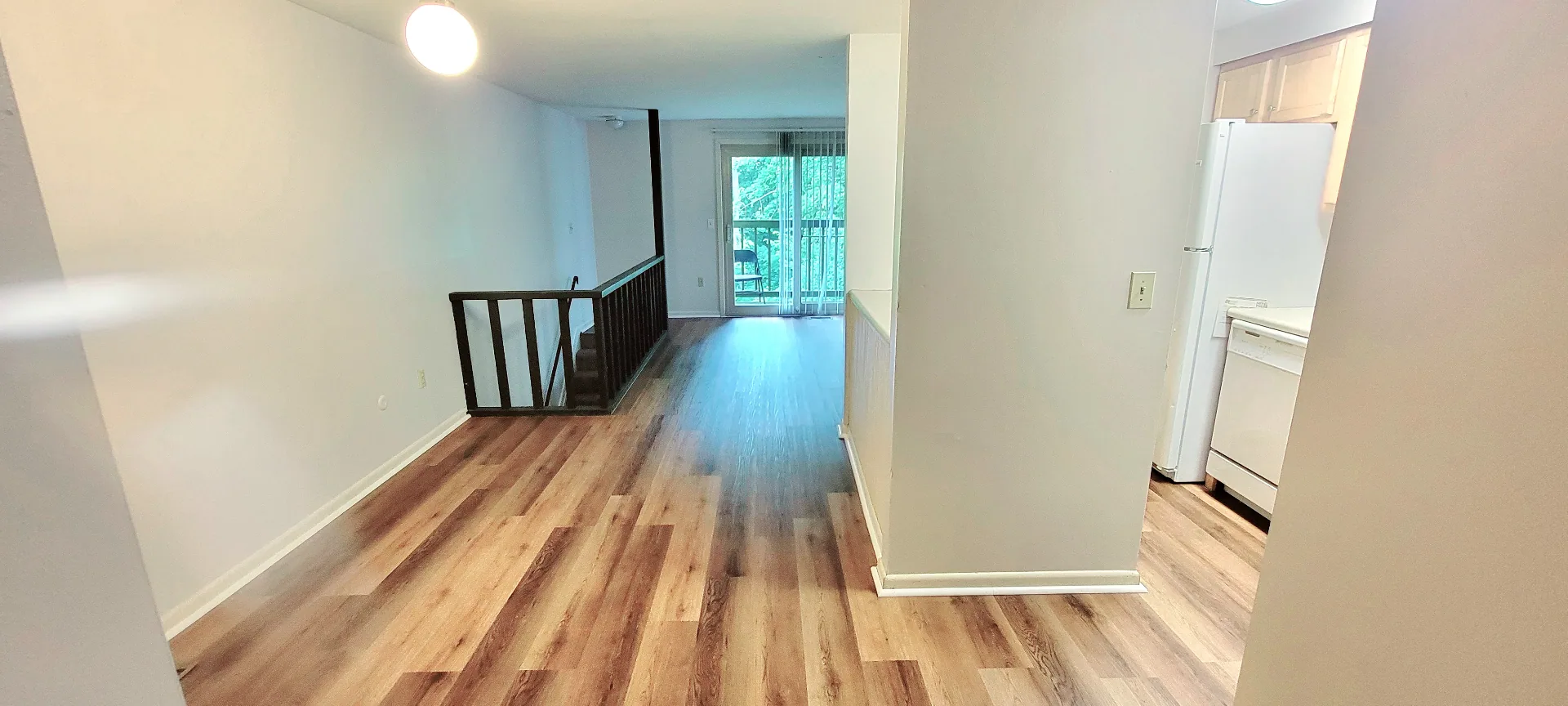 2022 Summit St. open living room with warm plank flooring, staircase railing, and balcony doors at the rear