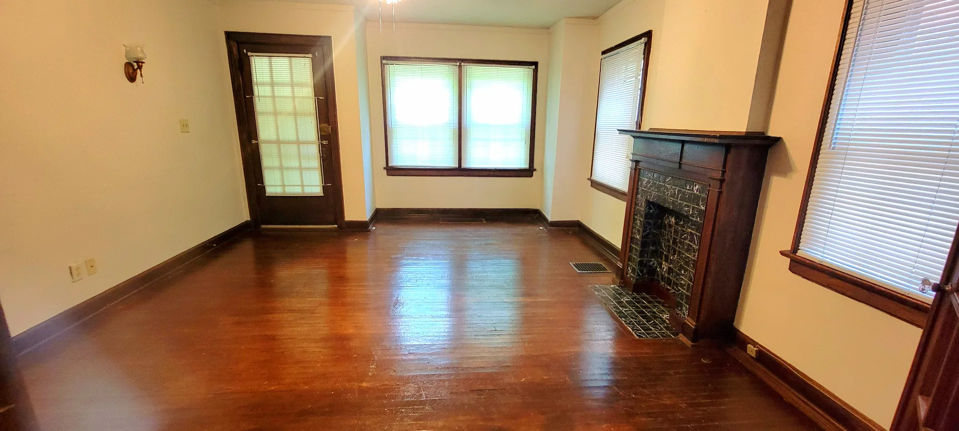 2048 Iuka Ave. A living room with decorative tile fireplace, hardwood floors, and bright front windows