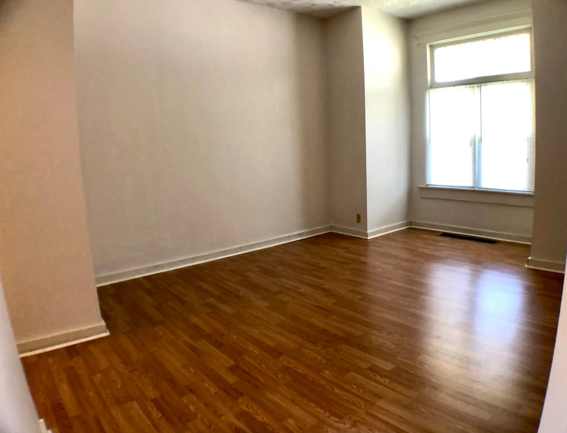 Unit A living room with hardwood floors, bright corner window and neutral walls